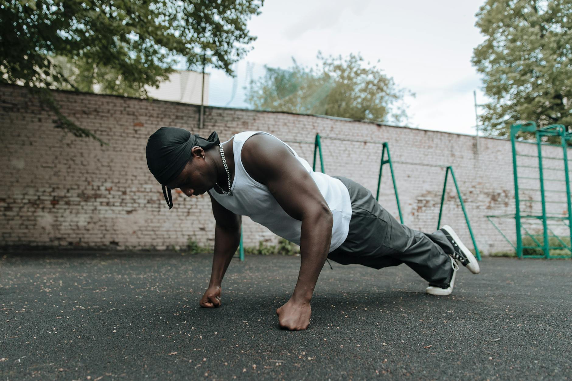 Adult man doing push-ups outdoors, focusing on fitness and strength. - bodyweight muscle building