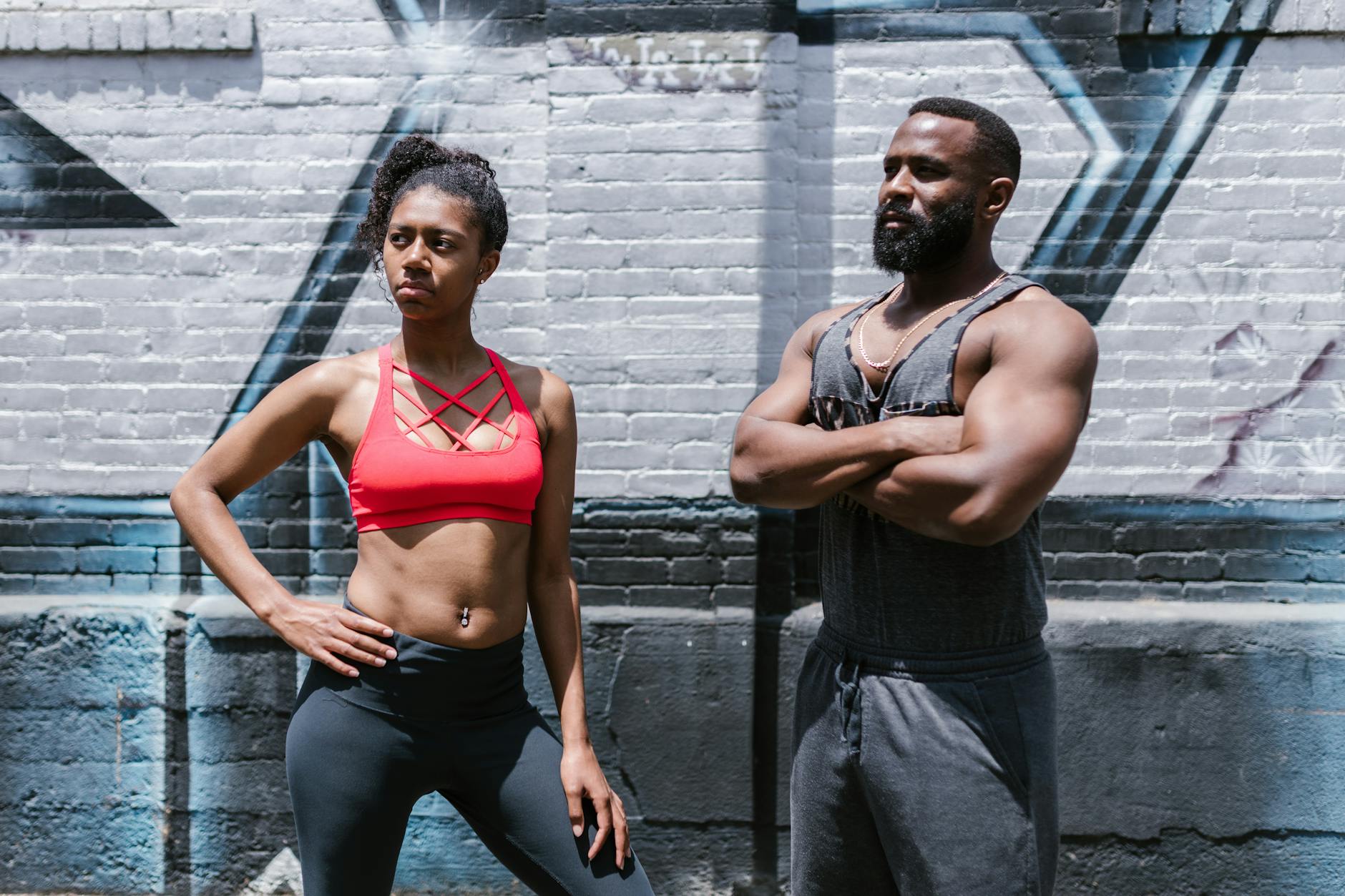 A fit man and woman pose confidently against a graffiti wall, embodying active lifestyle. - bodyweight muscle building