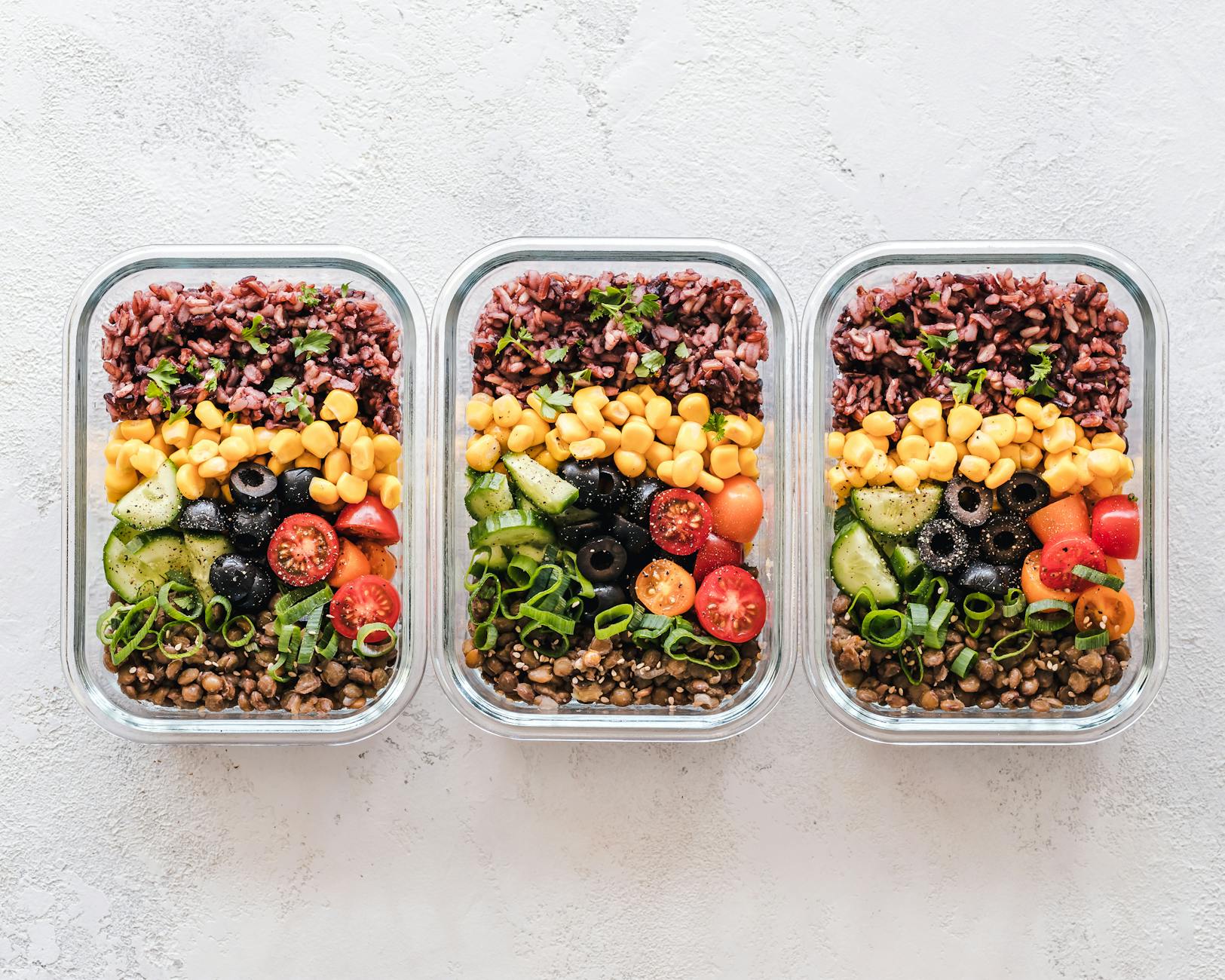 Colorful healthy meal prep with corn, olives, tomatoes, and lentils in glass containers. Perfect for mindful eating. - budget meal plans healthy