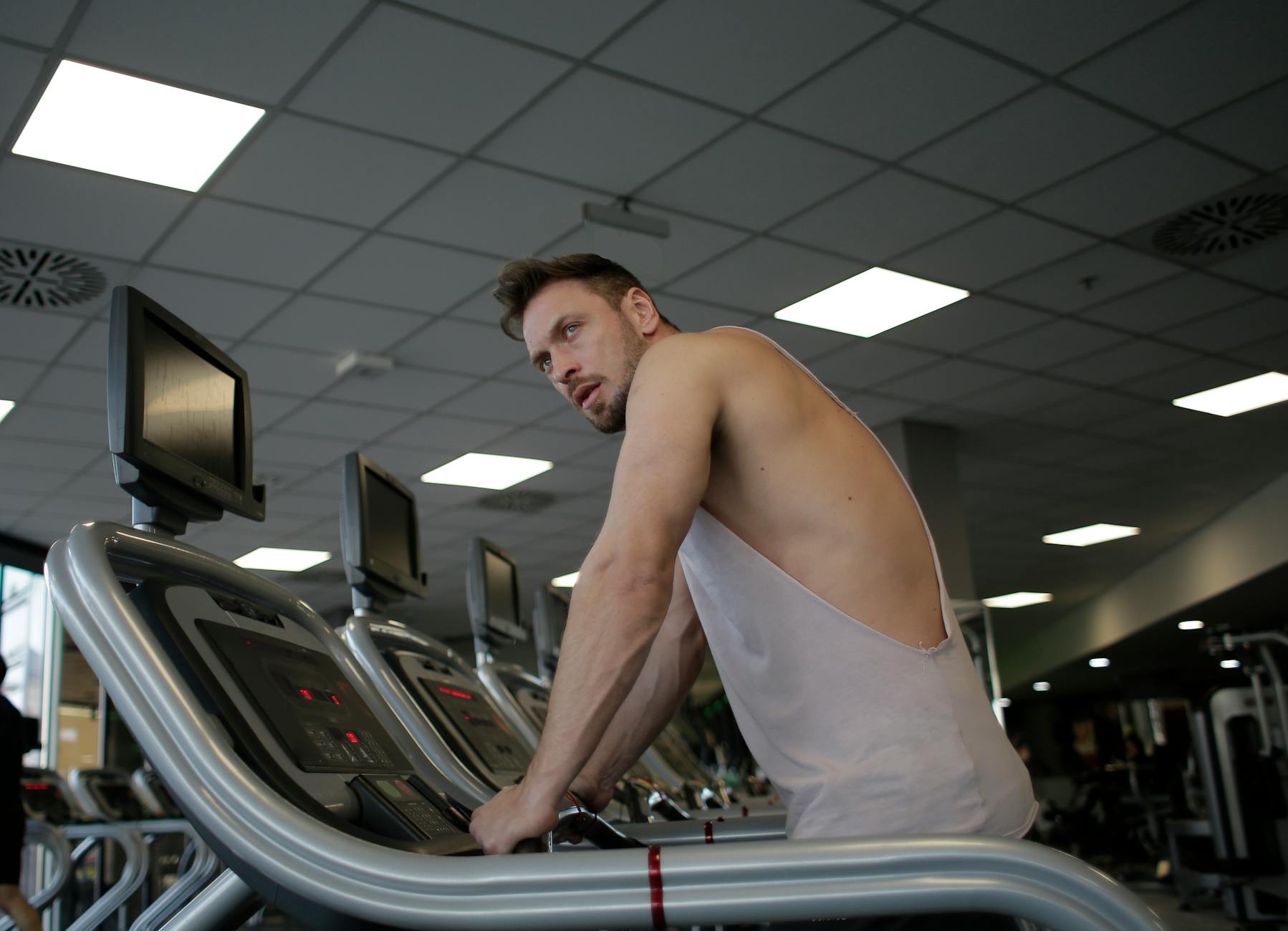 A focused man exercising on a treadmill in a modern gym setting, showcasing dedication and fitness. - cardio workouts for men