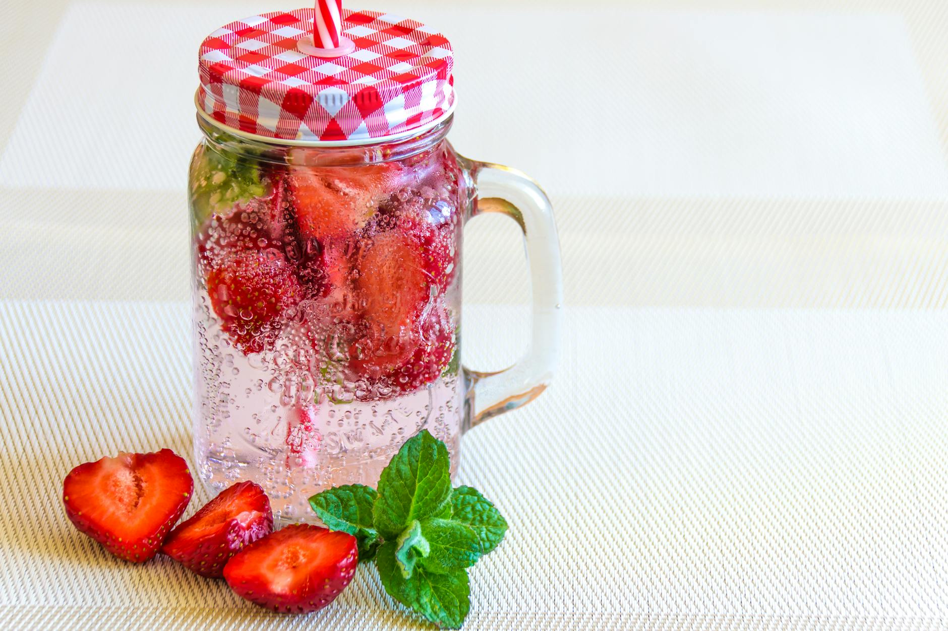 Mason jar of strawberry-infused sparkling water with mint, perfect for summer refreshment. - cold water swimming benefits