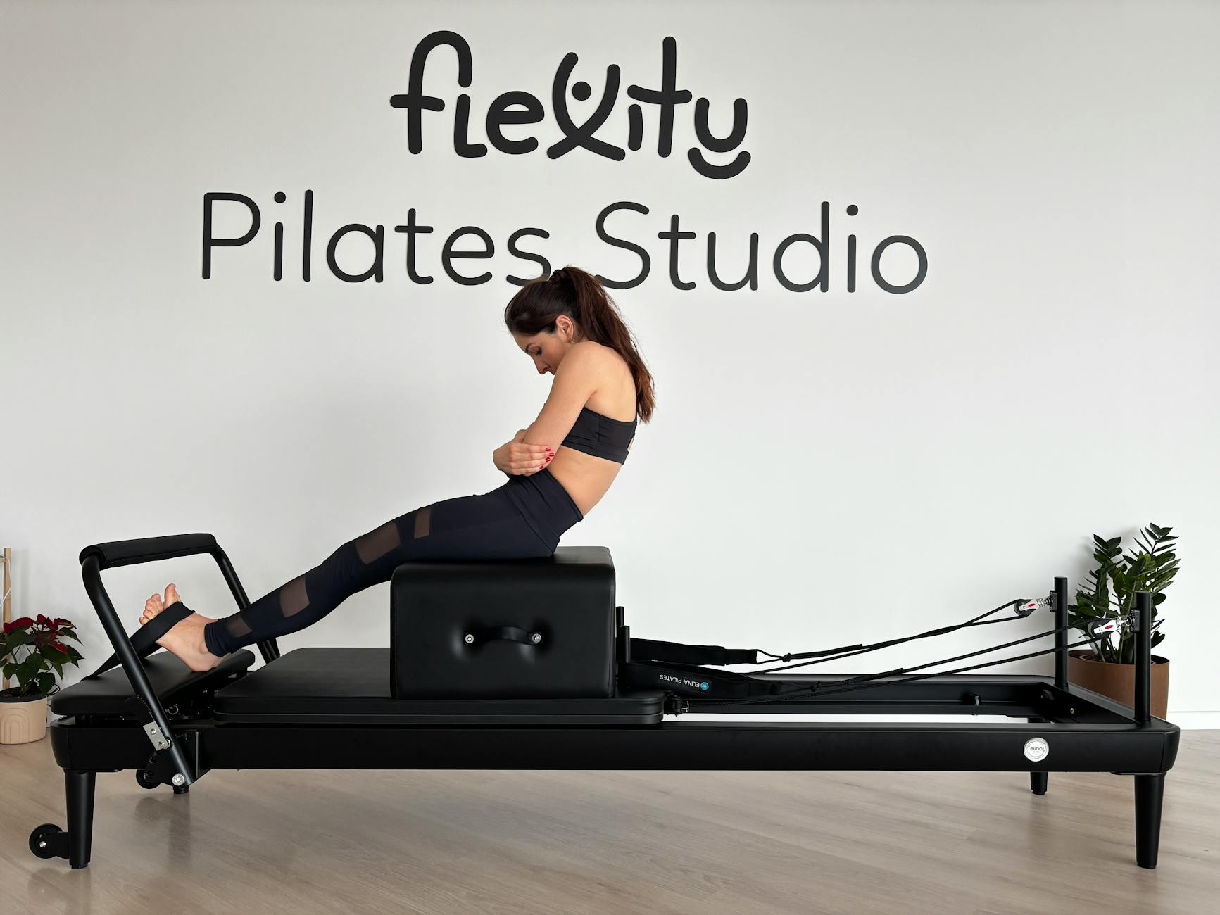 A woman is doing a Pilates workout on a reformer machine at a Pilates studio. - common pilates exercises