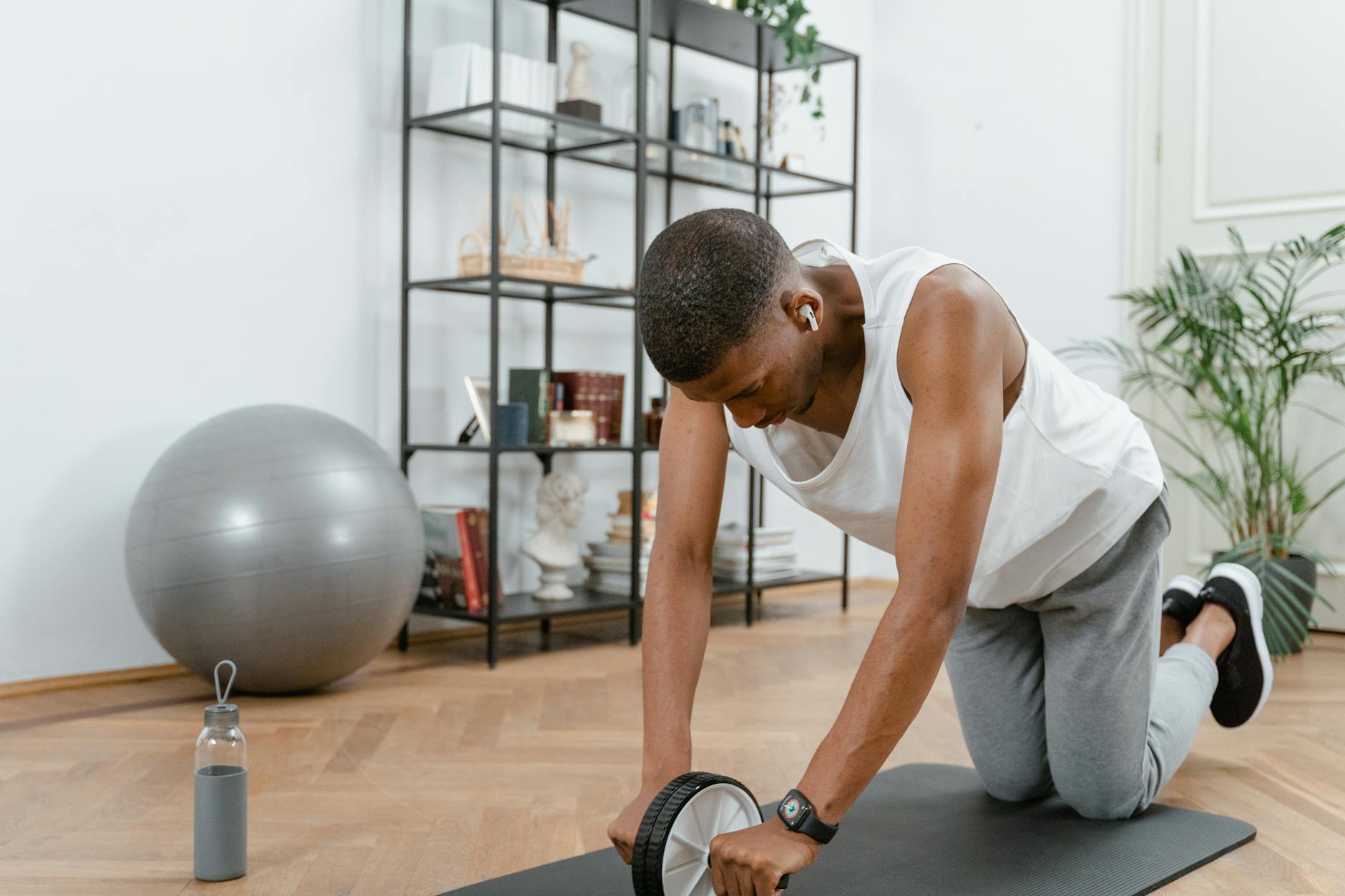 Adult male using an ab wheel for exercise in a home gym setting, focusing on fitness. - core workout at home