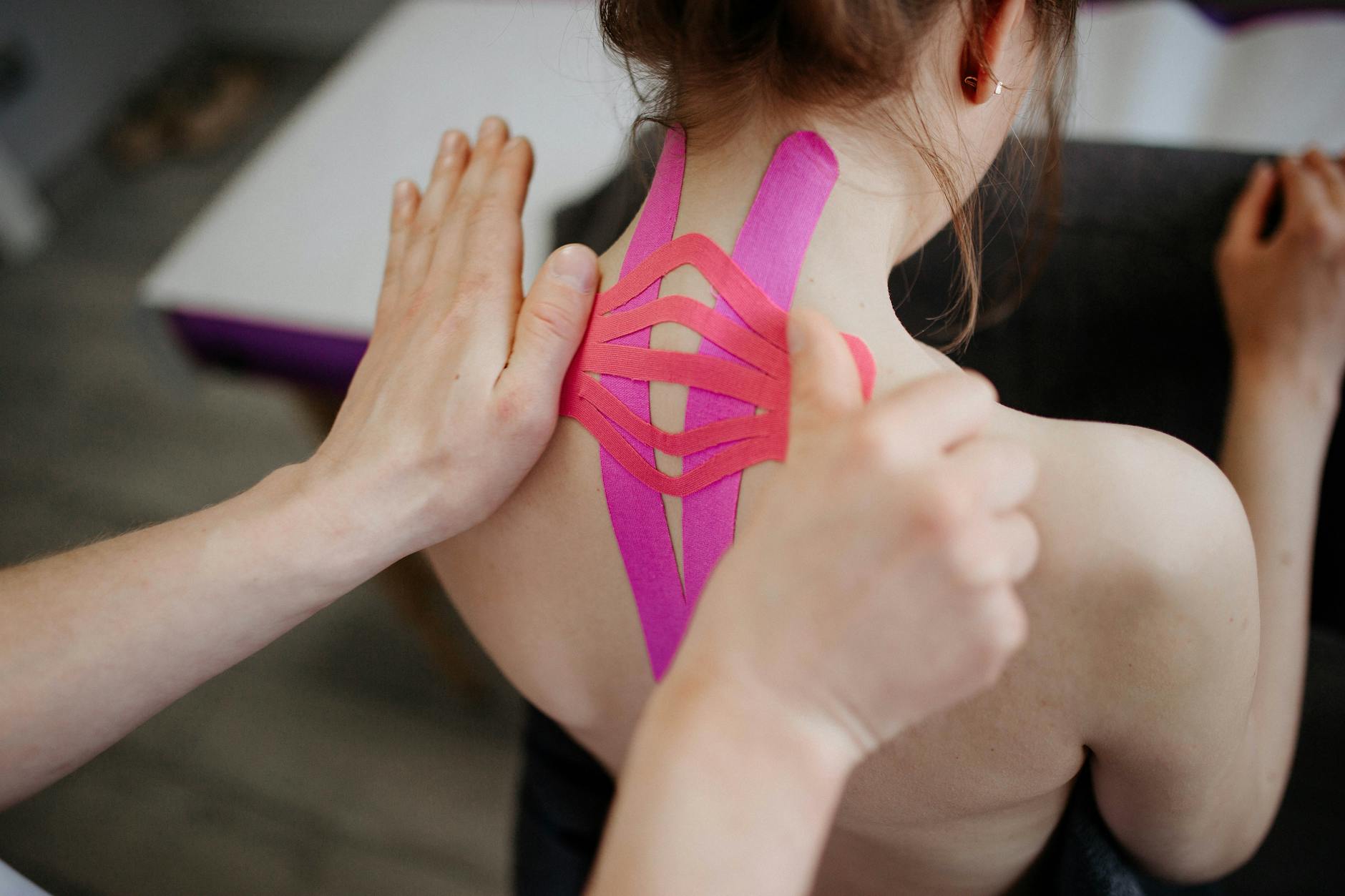 A close-up image of kinesio tape being applied to a person's back, showcasing healthcare and treatment. - correct shoulder posture exercises
