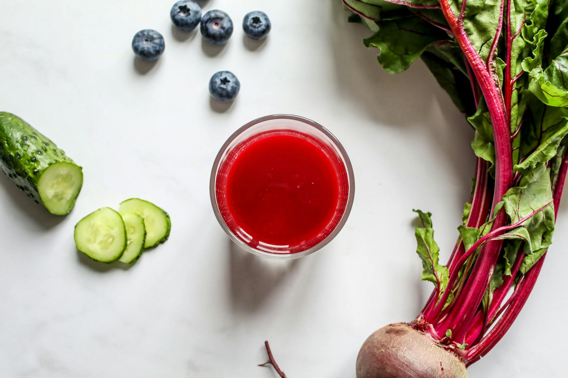 Top view of a vibrant beetroot juice with fresh cucumber and blueberries on a white background, perfect for a healthy lifestyle. - detox water recipes