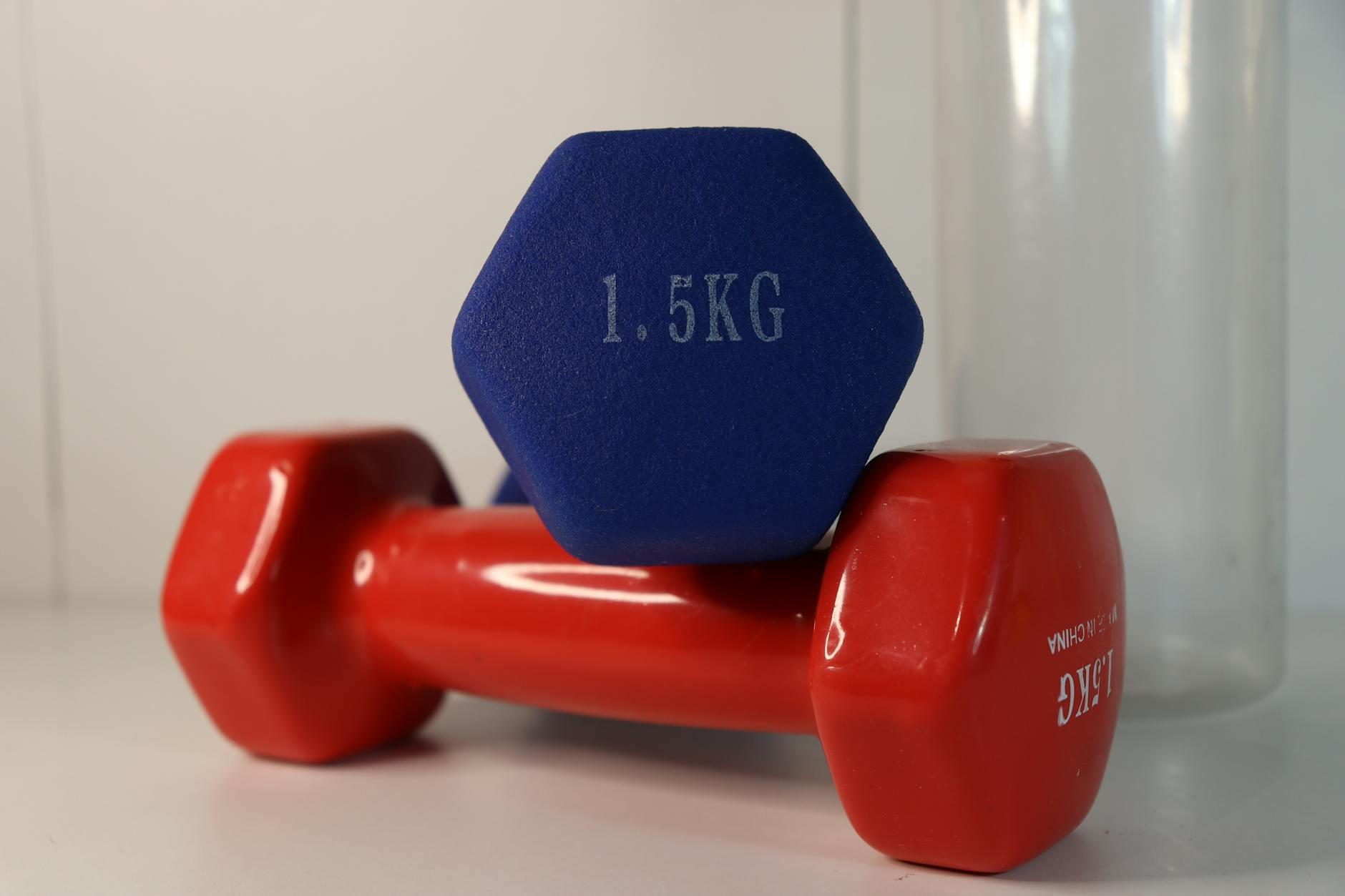 Two vibrant dumbbells positioned on a white surface with fitness emphasis. - dumbbell good morning