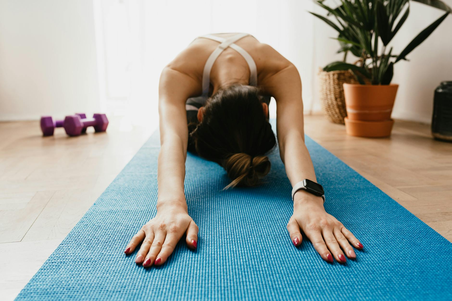 Woman doing a child's pose on a blue yoga mat at home, promoting fitness and wellbeing. - easy yoga for beginners
