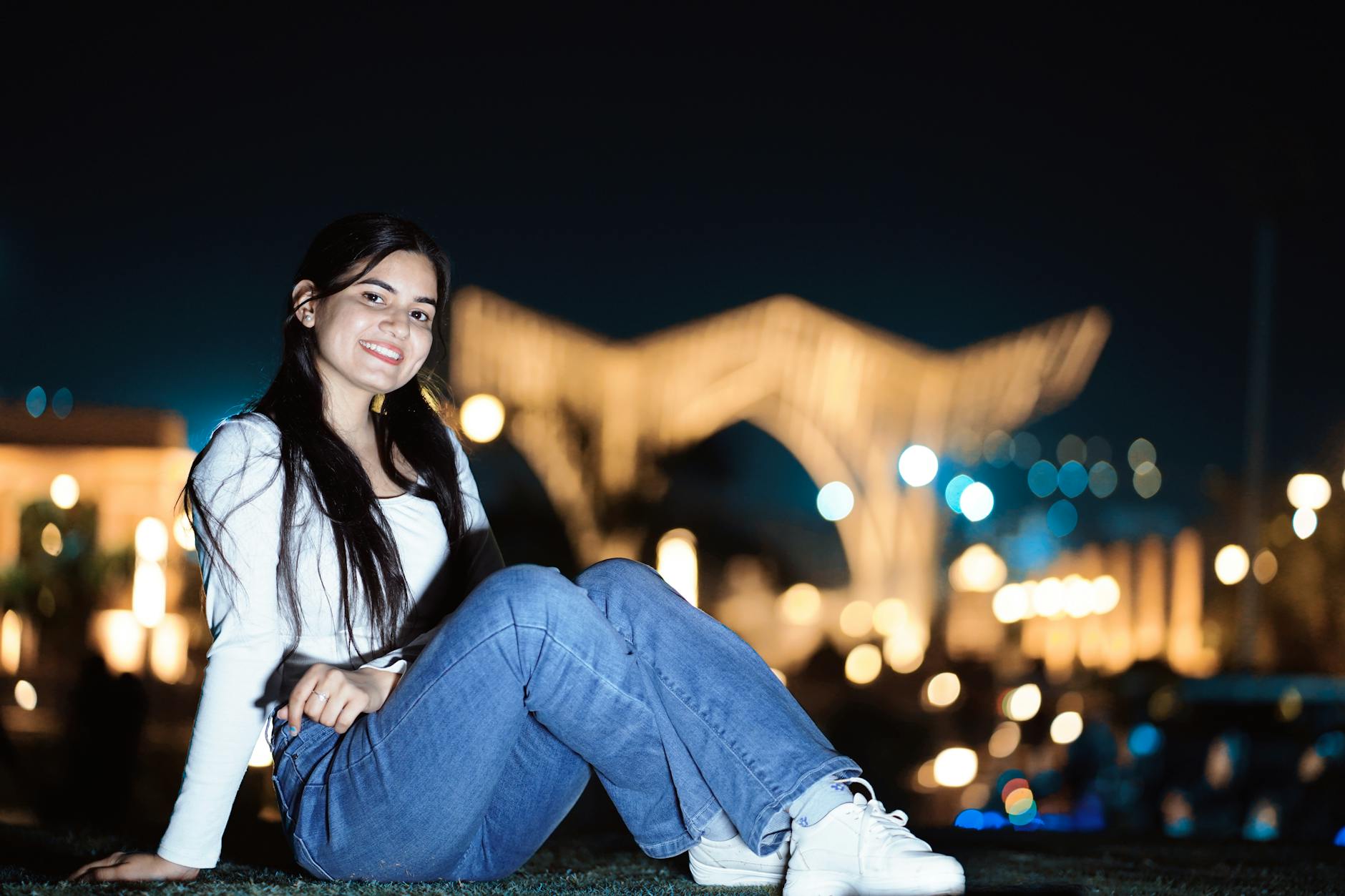 Young woman posing with a smile in an outdoor nighttime setting with blurred lights. - how to fix bad posture