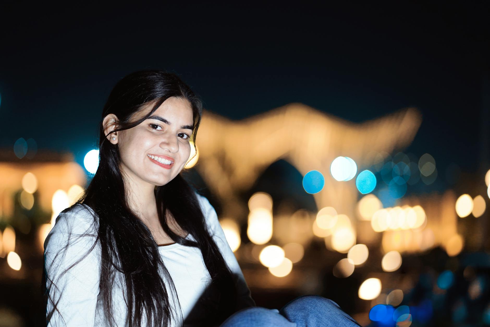 A young woman smiling against a blurry city lights backdrop at night. - how to fix bad posture