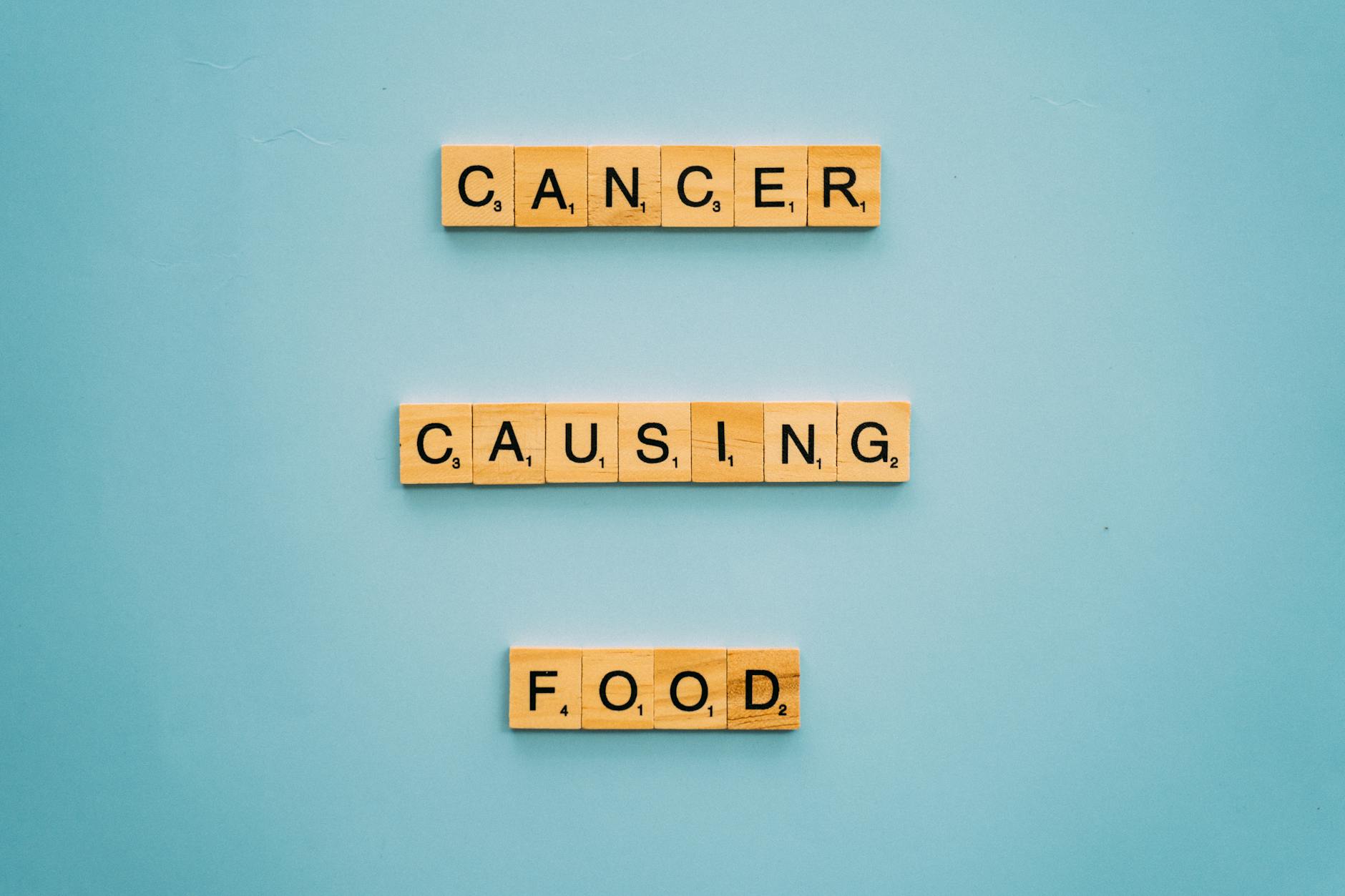 Conceptual image showing words 'cancer causing food' on Scrabble tiles against a blue background. - foods that cause inflammation