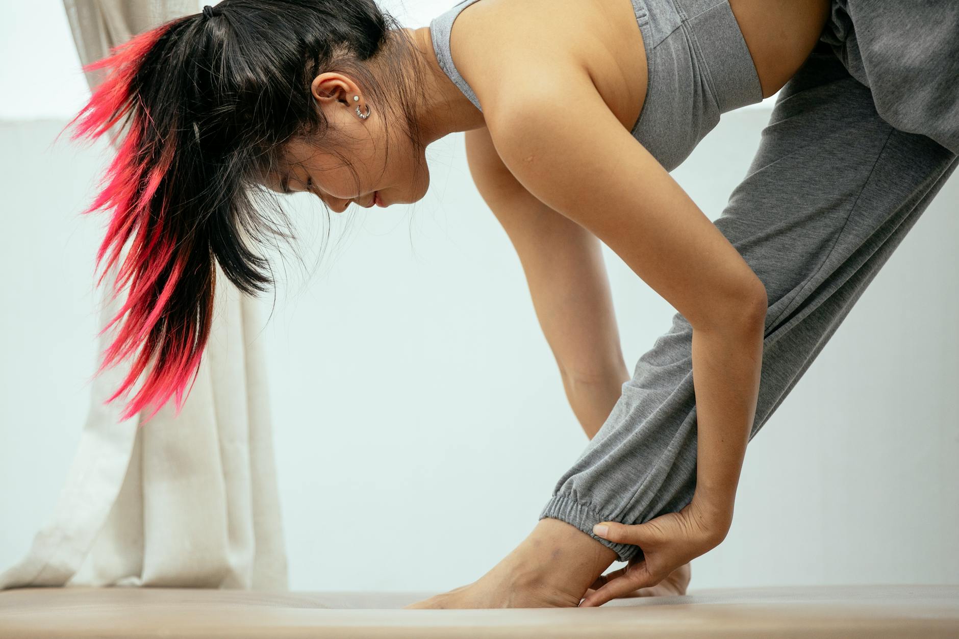 Side view ground level of peaceful ethnic female with pink hair practicing yoga in Parsvottanasana while stretching legs on terrace - forward head posture exercises