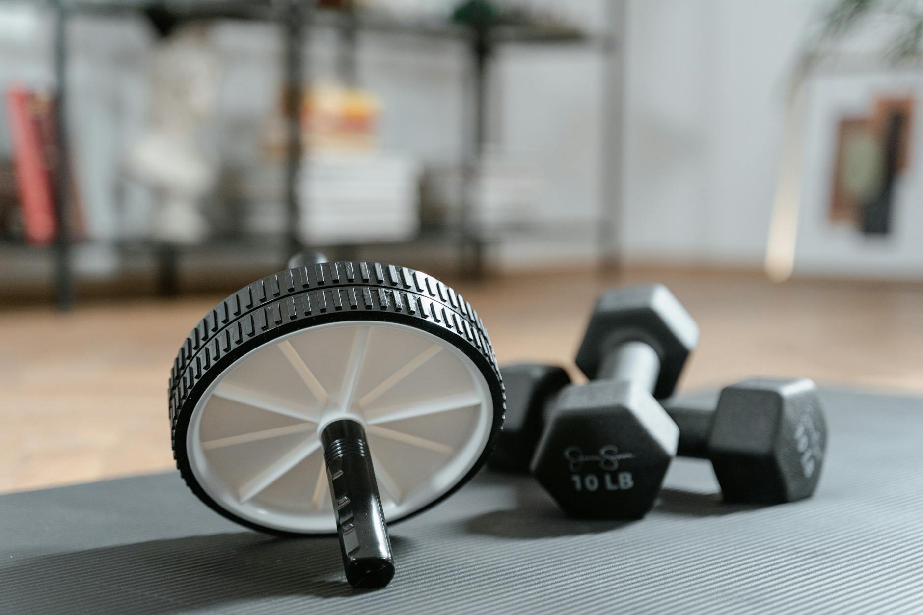 Ab roller and dumbbells on yoga mat, perfect for a home workout routine and healthy lifestyle. - gym core workout