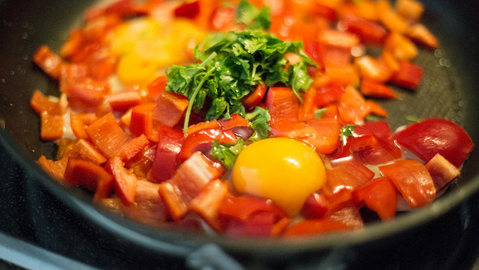 Close-up view of a colorful egg and bell pepper breakfast skillet with herbs. - healthy breakfast eggs