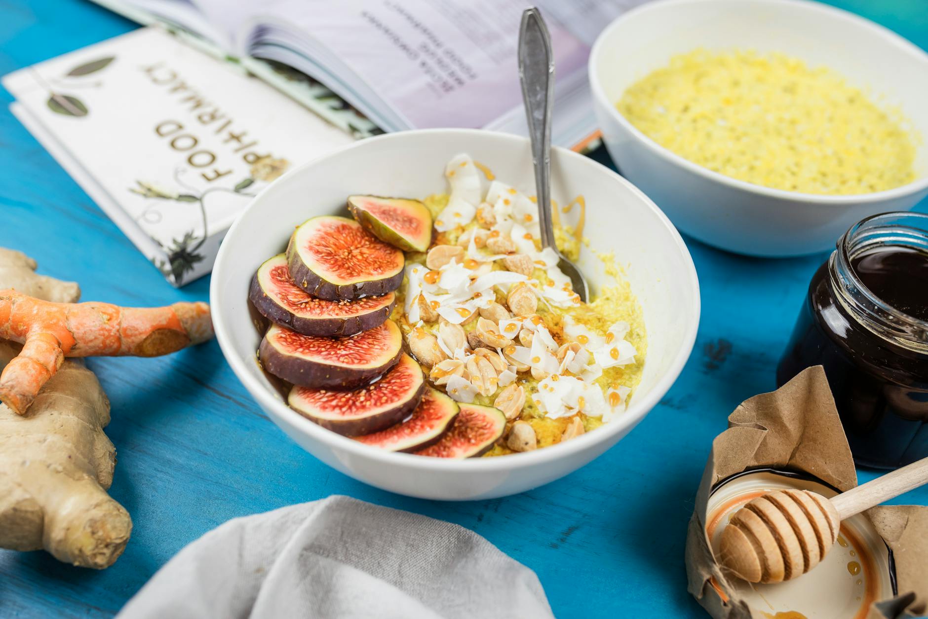 Healthy breakfast bowl with figs, nuts, and turmeric on a blue table with ginger and honey. - healthy breakfast meal prep