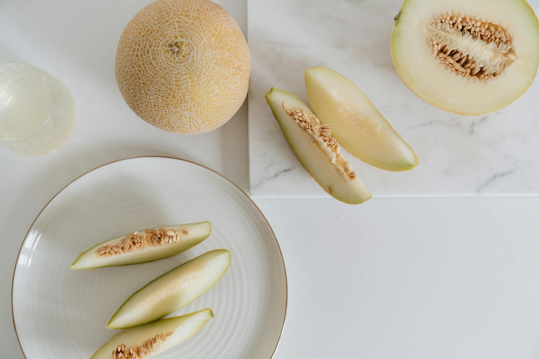 Freshly sliced cantaloupe melon arranged on a marble countertop and plate. - healthy snack ideas