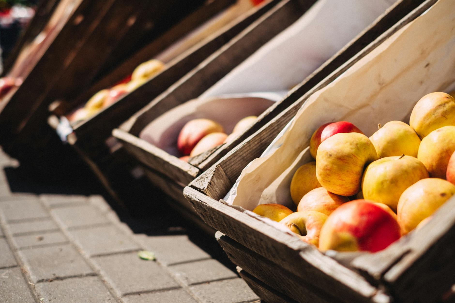 Vibrant apples displayed in rustic wooden crates at a lively outdoor market. - healthy snacks to buy