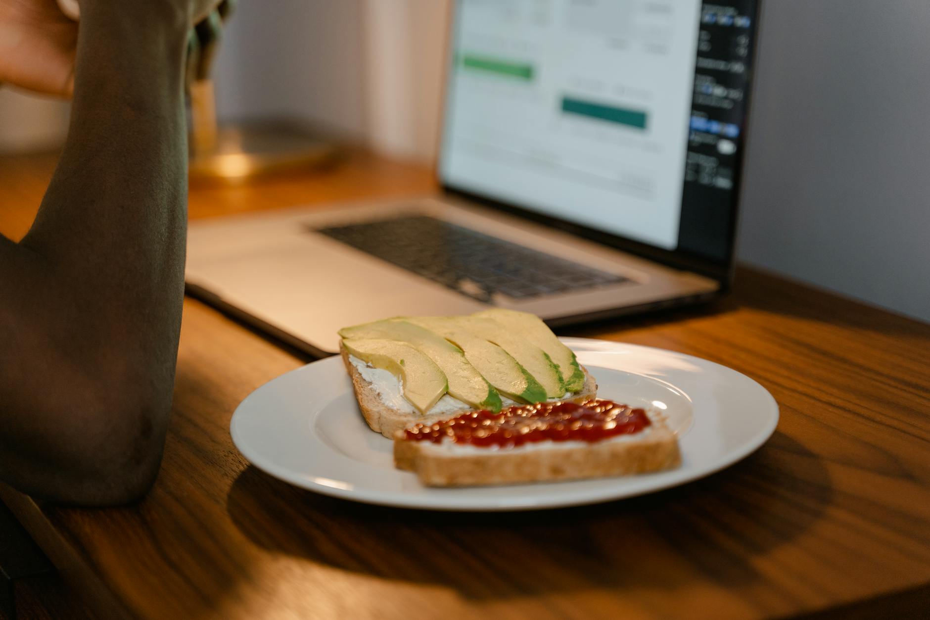 A workspace setup with avocado toast next to a laptop, perfect for remote work inspiration. - healthy work snacks