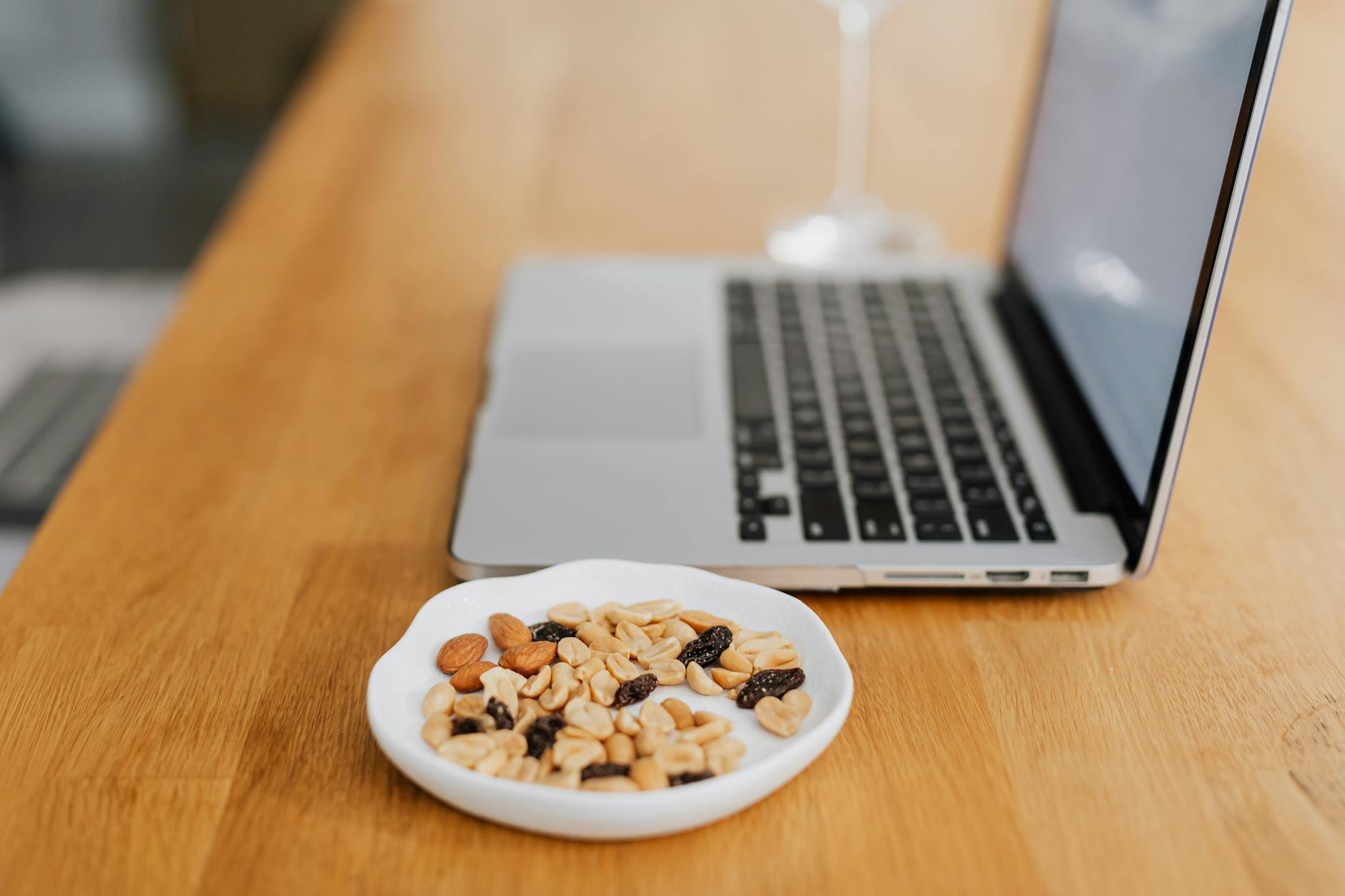 Close-up of a healthy snack beside a laptop on a wooden table, perfect for productive work breaks. - healthy work snacks