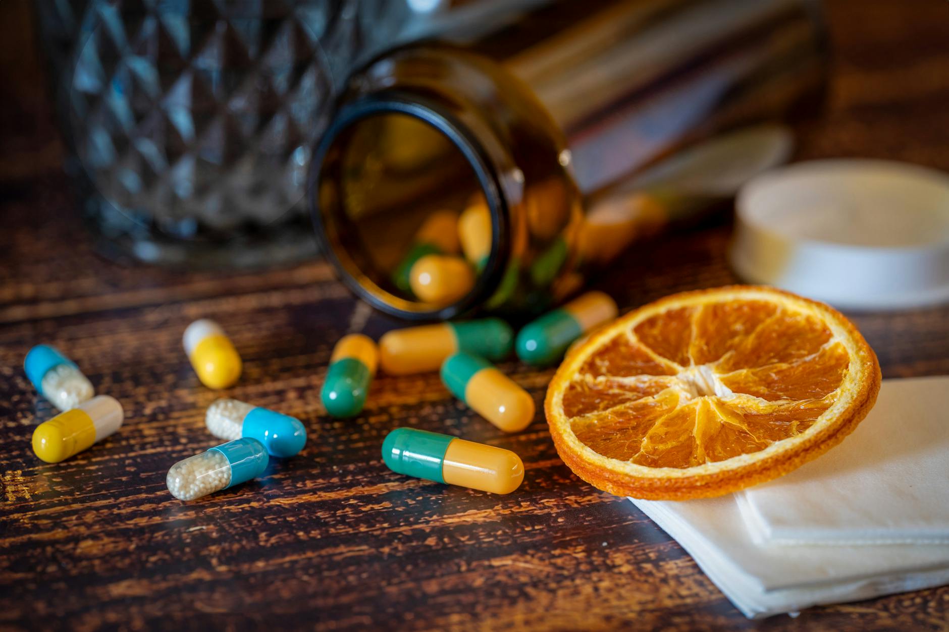 Close-up of vitamins, pills, and dried orange slice for cold relief. - immune boosting foods list