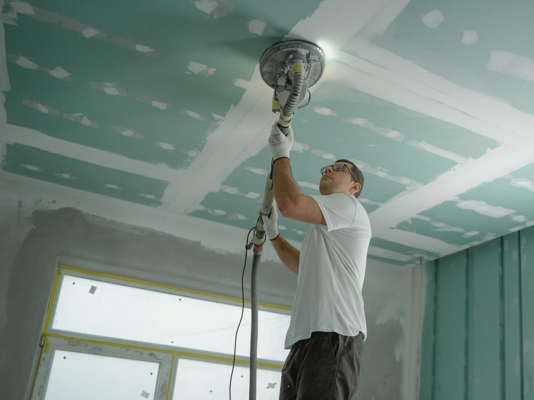 A professional worker sanding the ceiling during a home renovation project. Indoor construction setting. - improve gut health
