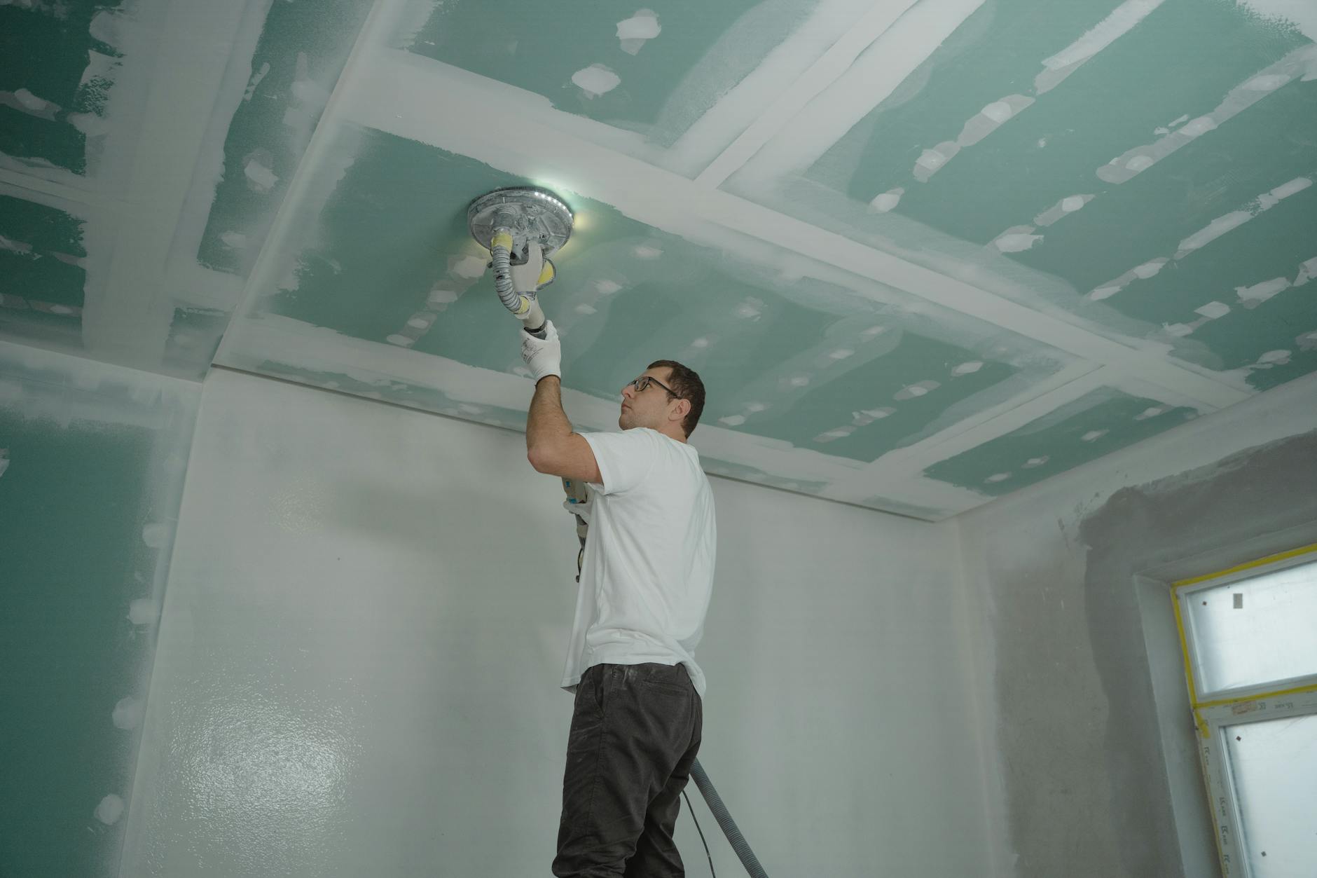 A worker expertly polishes a ceiling indoors, demonstrating home renovation skills. - improve gut health