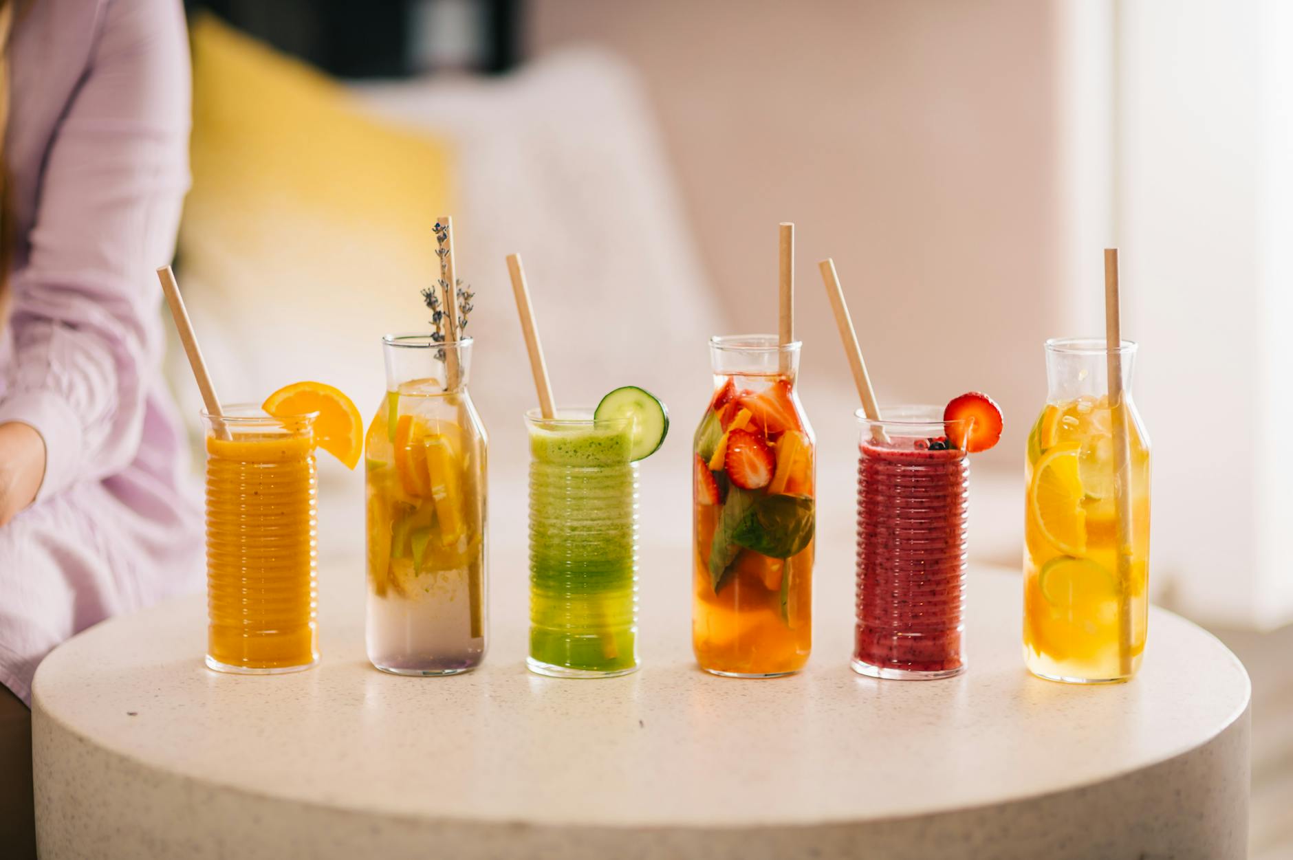 A variety of refreshing fruit drinks in jars with straws arranged on a table. - kid-friendly smoothie recipes