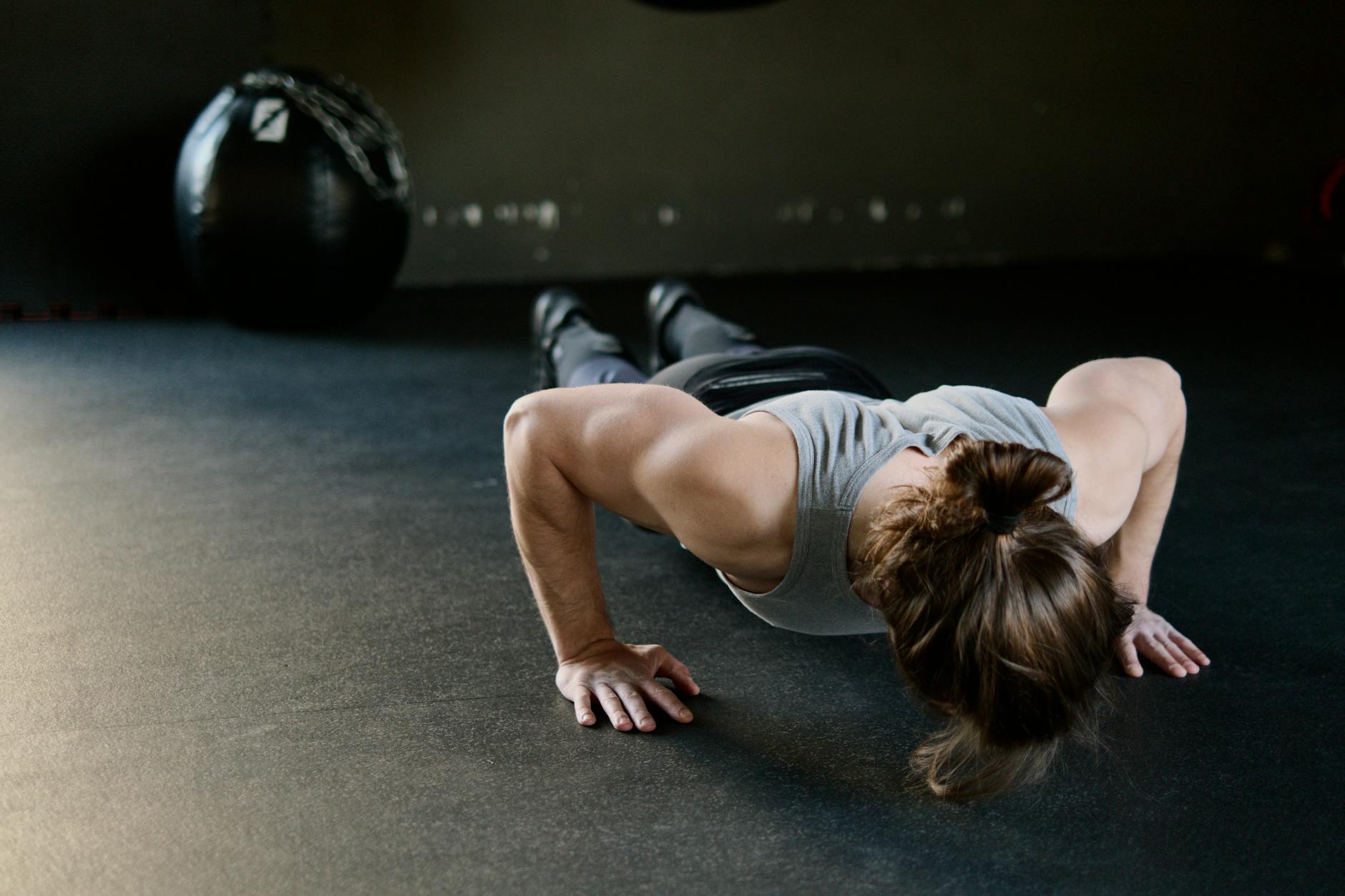 Strong male engaged in push-up exercise on gym floor, showcasing upper body strength. - men's workout routine