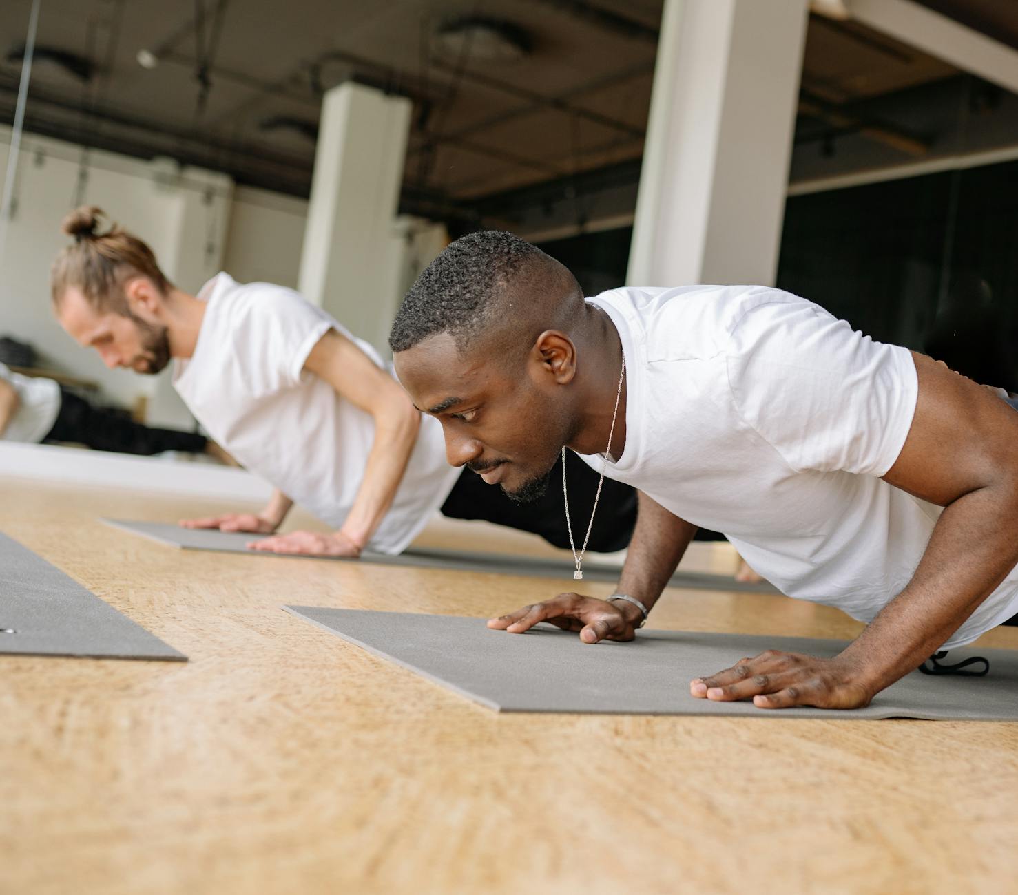 Two adult men working out indoors, focusing on push-ups for strength training. - morning workout for men
