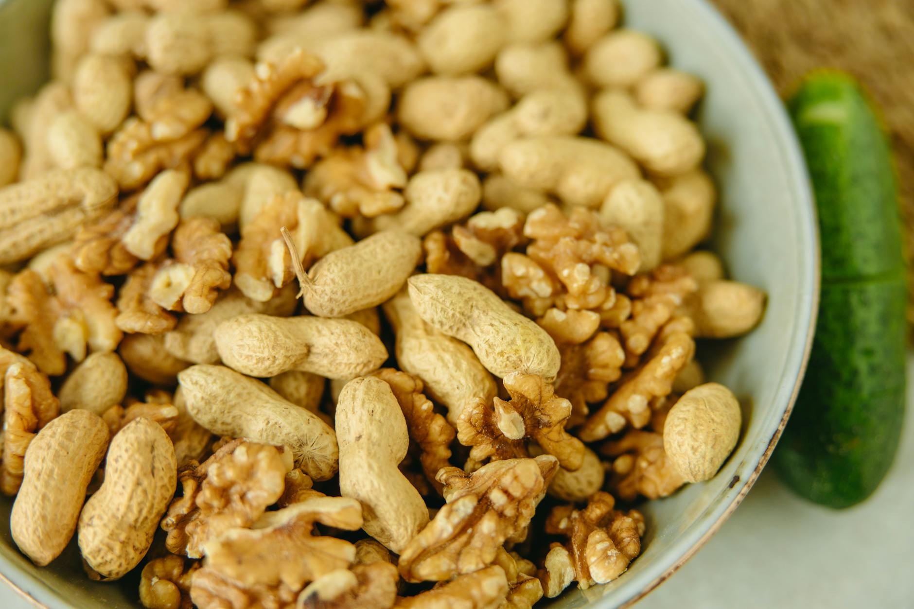 A close-up shot of peanuts and walnuts in a light green bowl, ideal for food photography. - plant based protein diet plan
