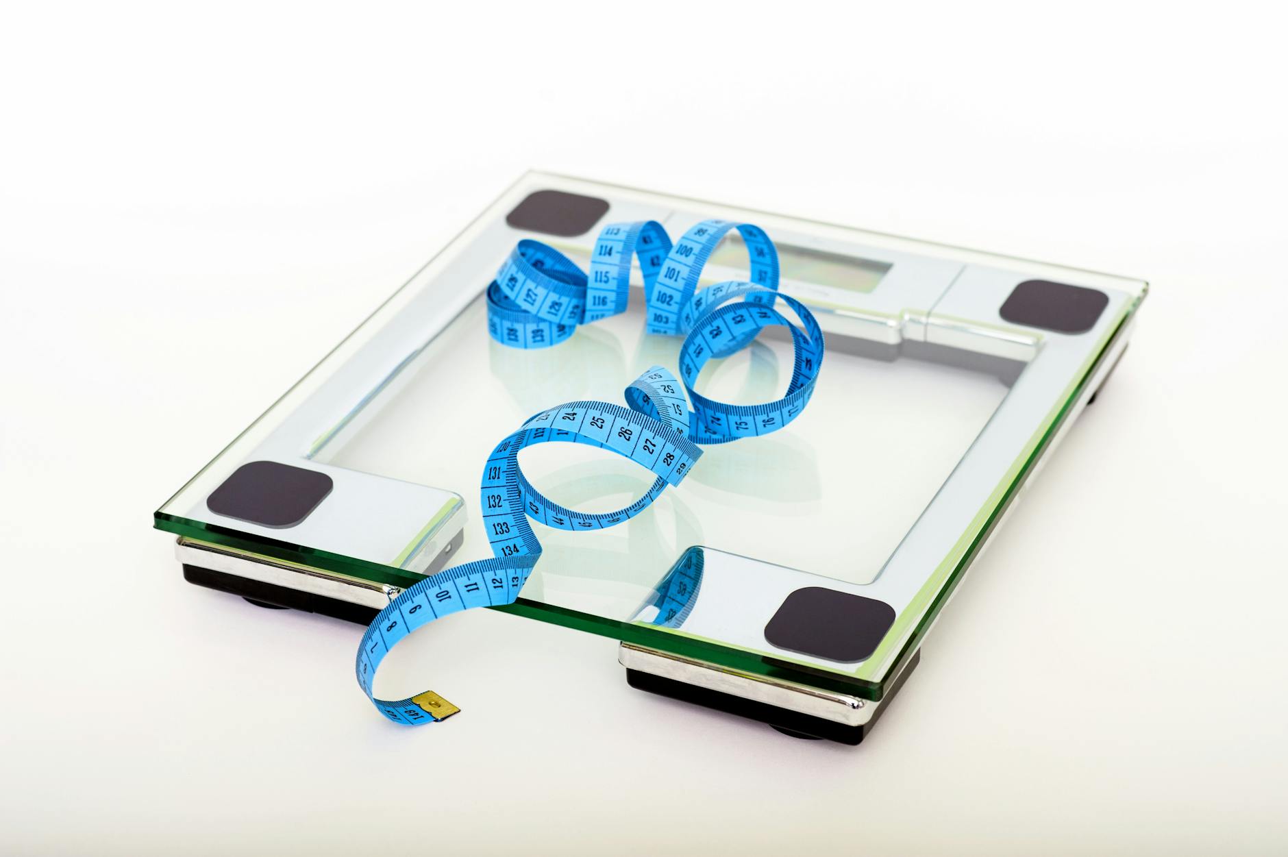 A digital glass weighing scale with a blue measuring tape, symbolizing weight management. - reddit weight loss