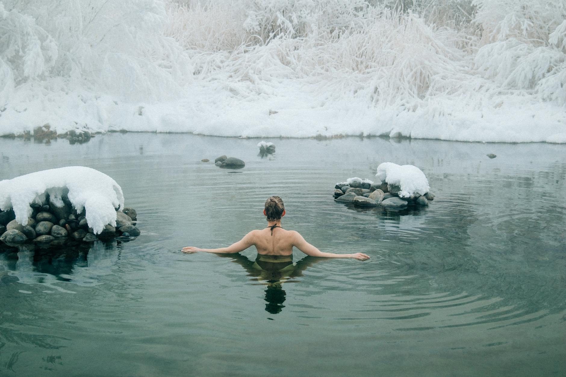 A young woman enjoying a swim in a tranquil winter lake surrounded by snow. - swimming benefits for children
