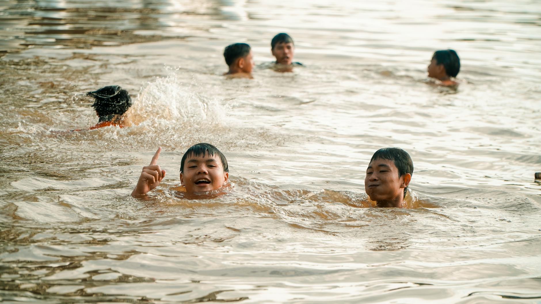 Children playing and splashing in a lake in Pontianak, Indonesia, enjoying a sunny day. - swimming benefits for children