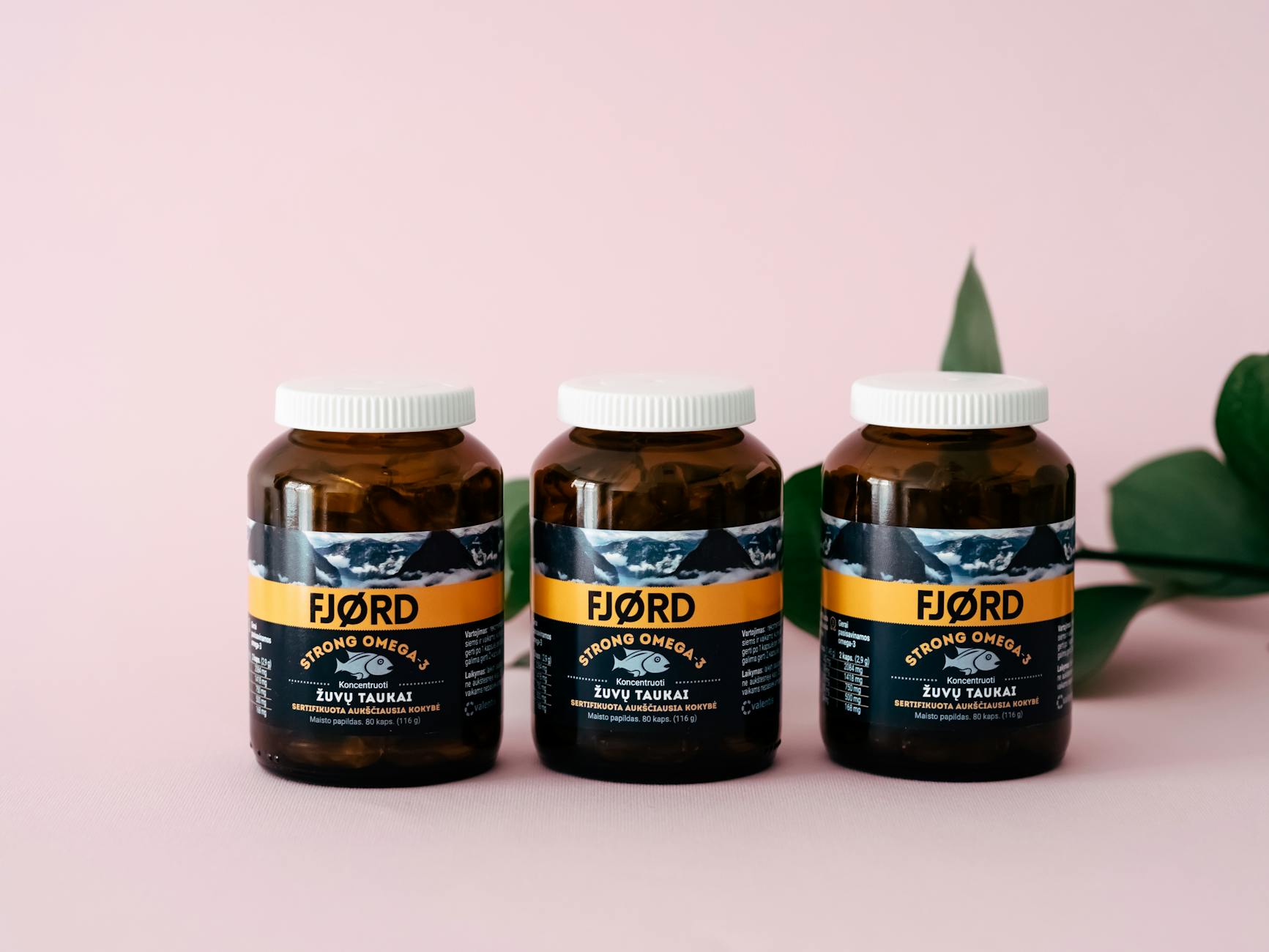 Three FJORD Omega-3 supplement bottles on a pink backdrop with greenery accents. - swimming benefits for health
