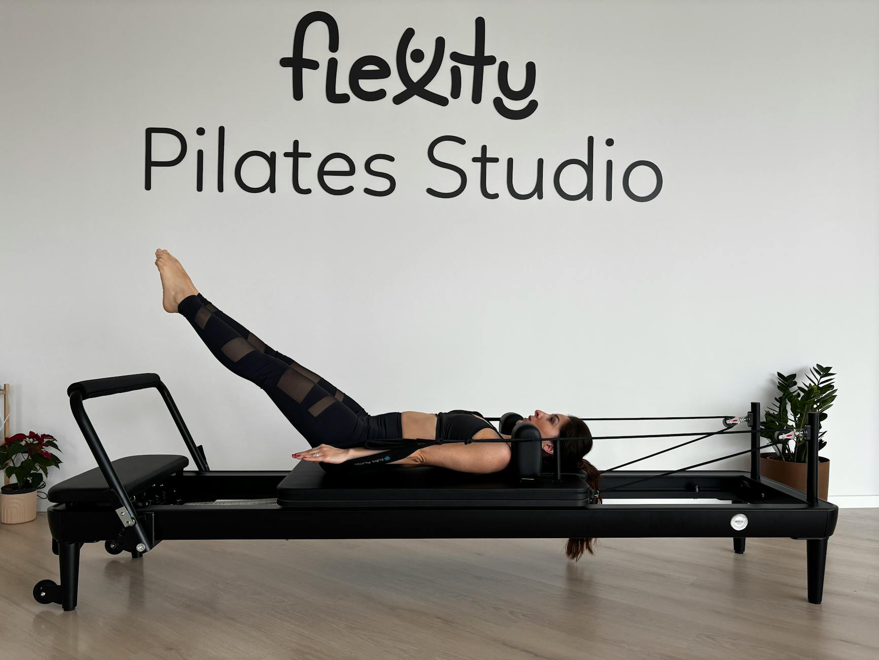 A woman performing Pilates exercises on a reformer in a modern fitness studio. - wall pilates exercises
