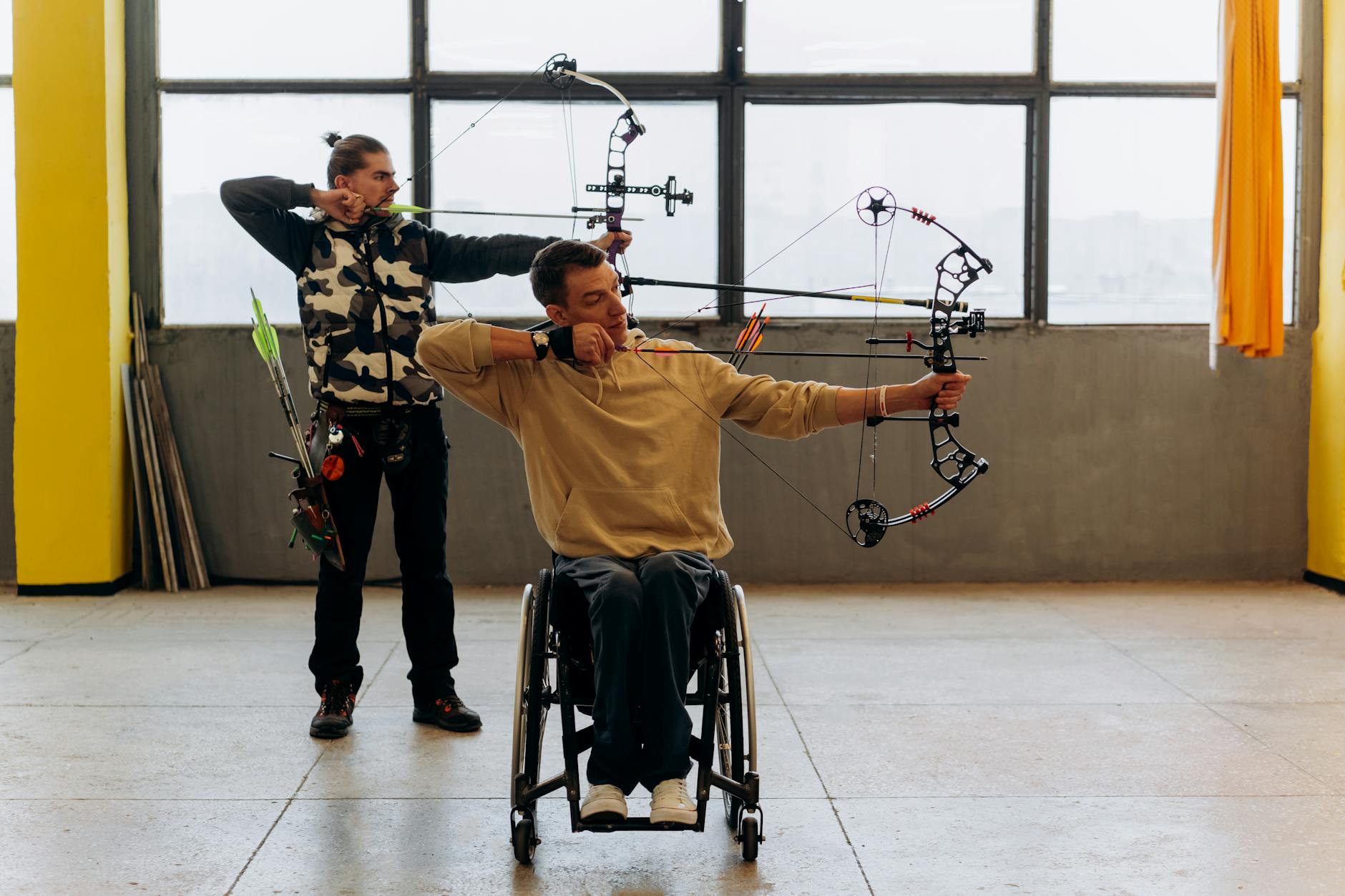 Two archers practice indoors, one using a wheelchair, showcasing determination and skill. - 30 day fitness challenge