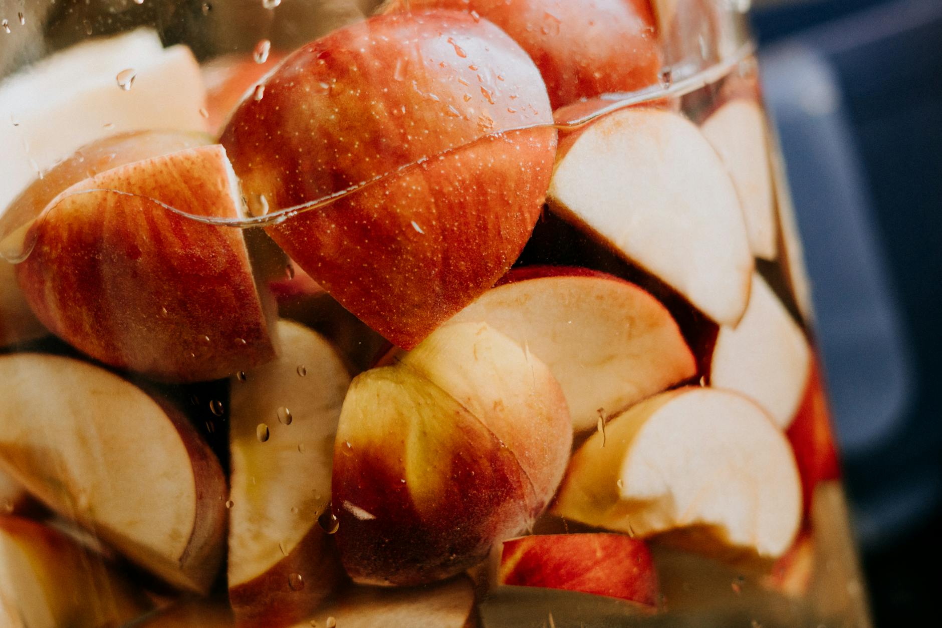 Close-up of fresh red apple slices immersed in water, showcasing their juicy texture. - apple detox water