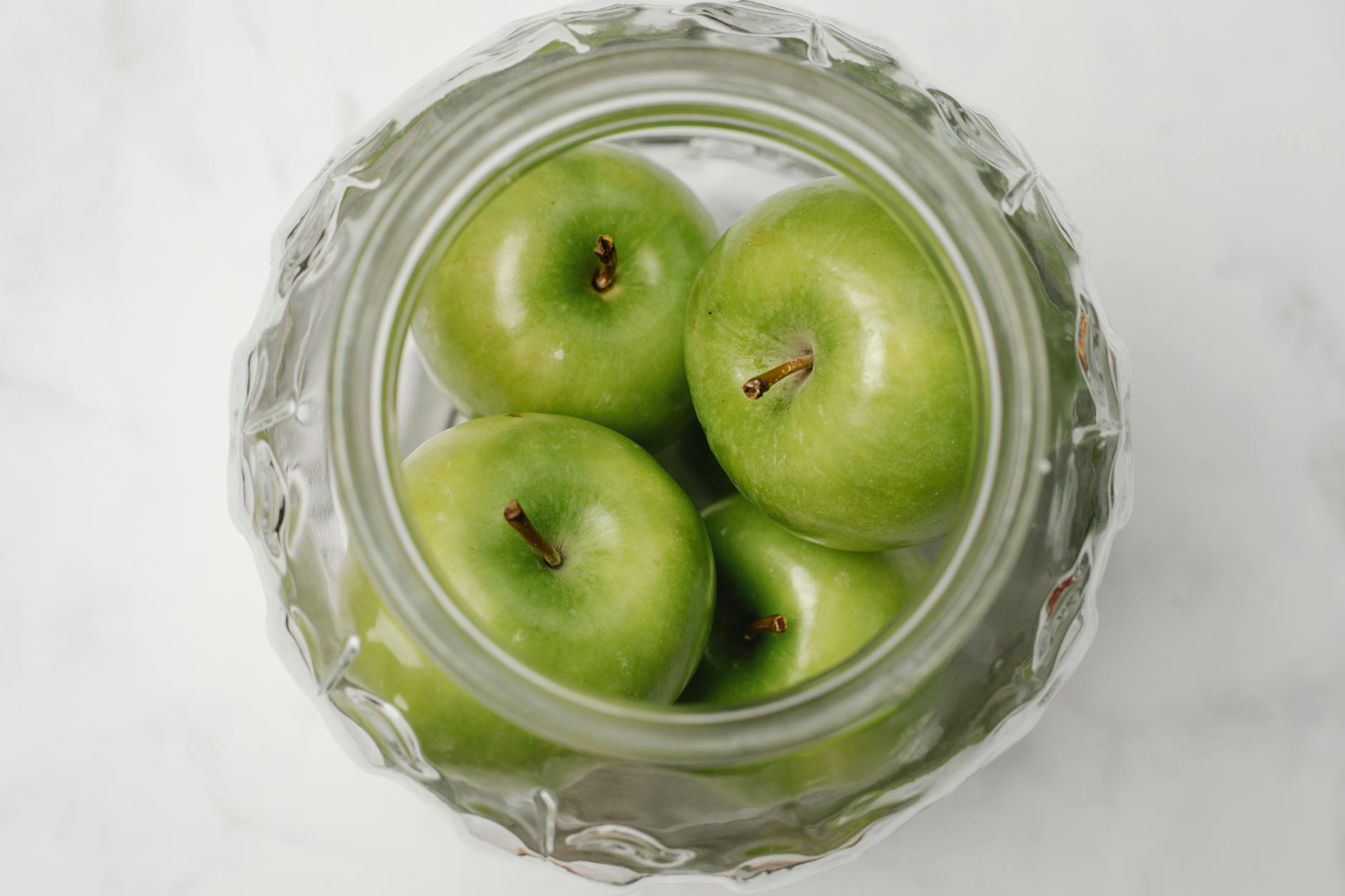 Top view of green apples inside a glass jar, showcasing a healthy and organic composition. - apple detox water