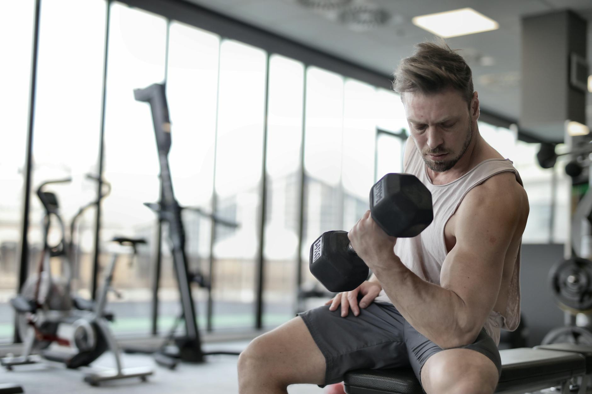 Focused man working out with a dumbbell in a well-equipped gym for strength training. - arm workout routine