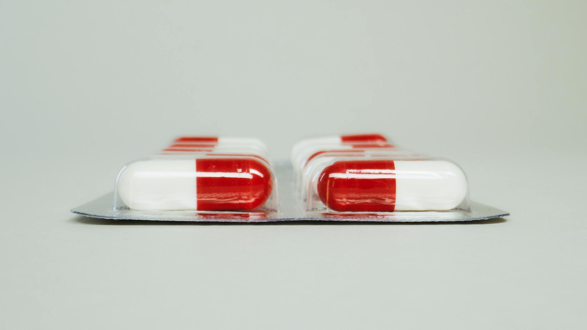 Blister pack of red and white capsules isolated against a simple background. - back pain medicine