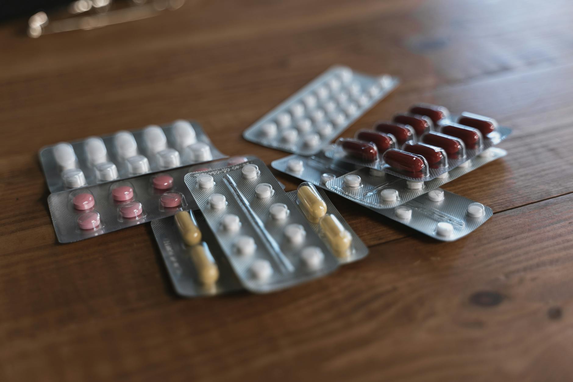 A variety of pills in blister packs displayed on a wooden surface. Ideal for health-related content. - back pain medicine