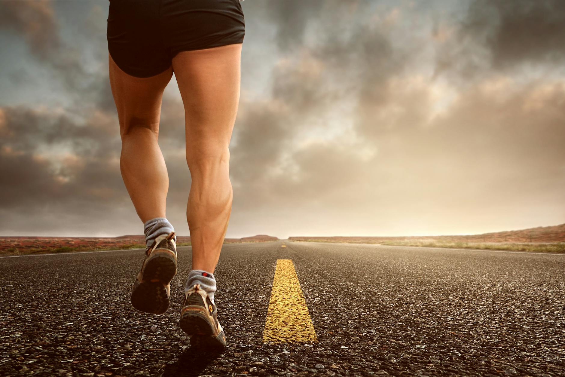 Runner's legs on a road during a sunset, symbolizing endurance and outdoor fitness training. - beginner running tips