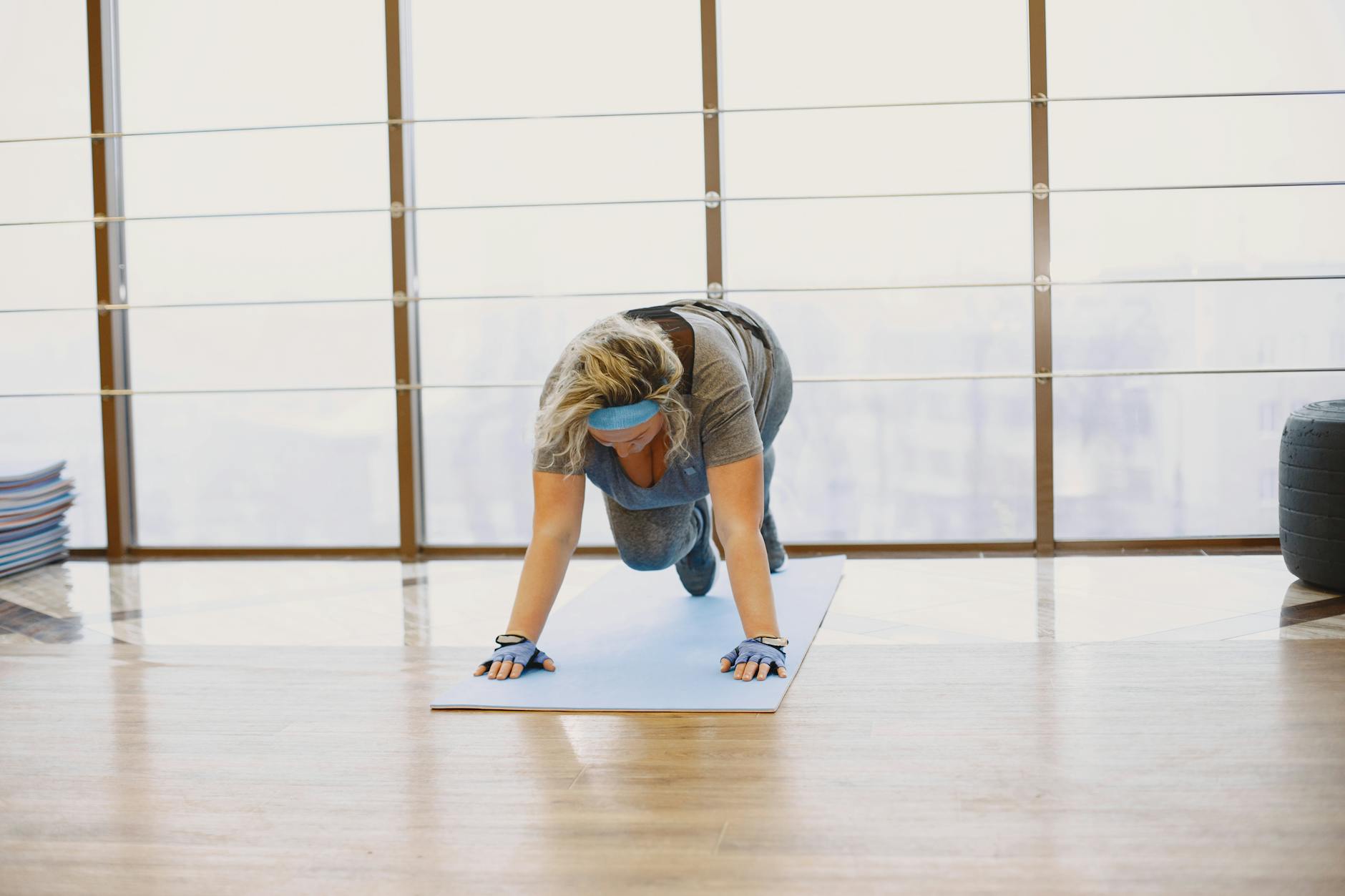 A woman performing a workout on a yoga mat in a bright indoor gym setting. Fitness and healthy lifestyle concept. - beginner workout routines