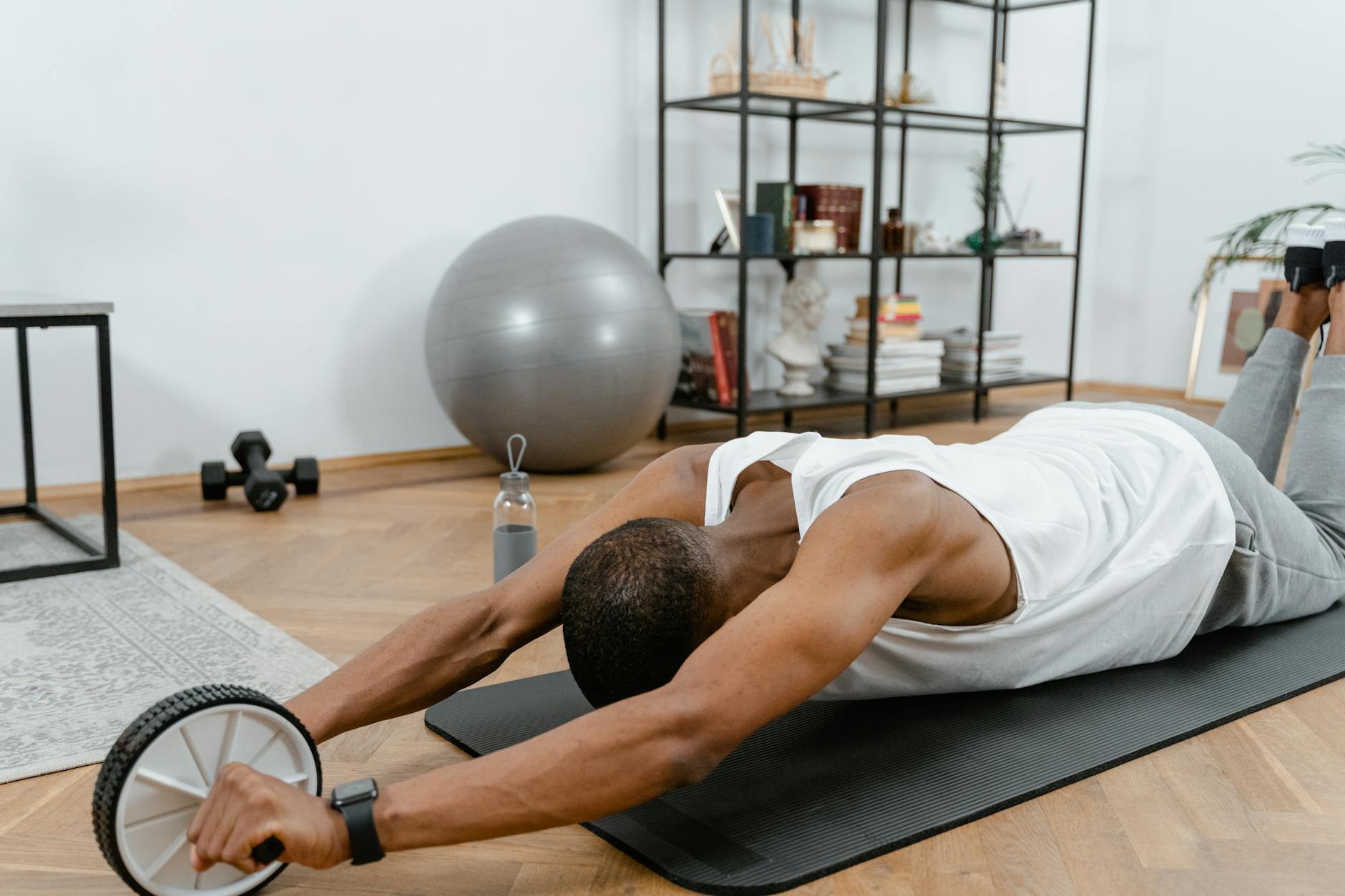 A man performs an ab roller workout indoors, emphasizing healthy lifestyle and fitness. - best ab workout
