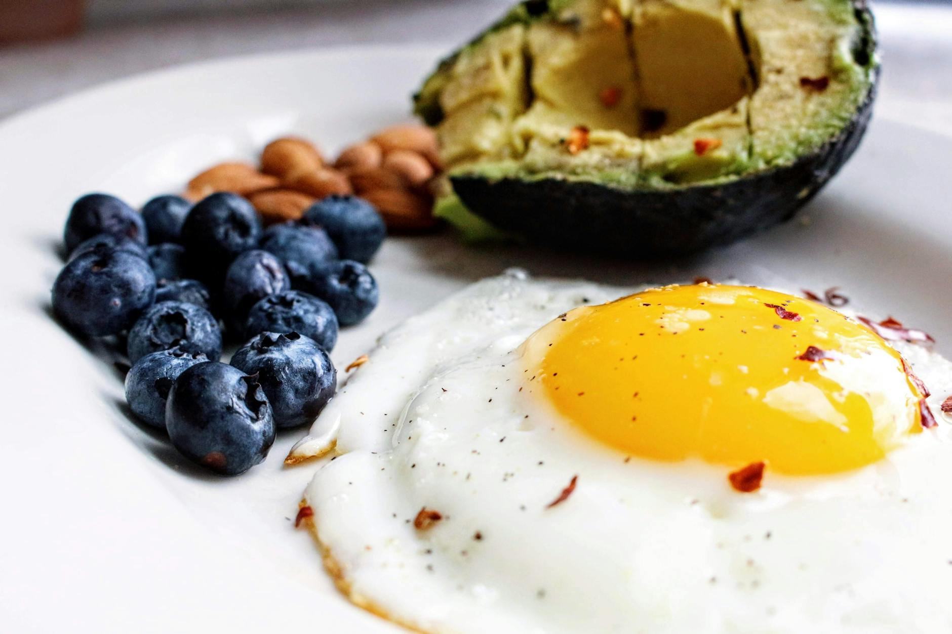 A nutritious breakfast featuring a fried egg, avocado, blueberries, and almonds. - best keto diet recipes