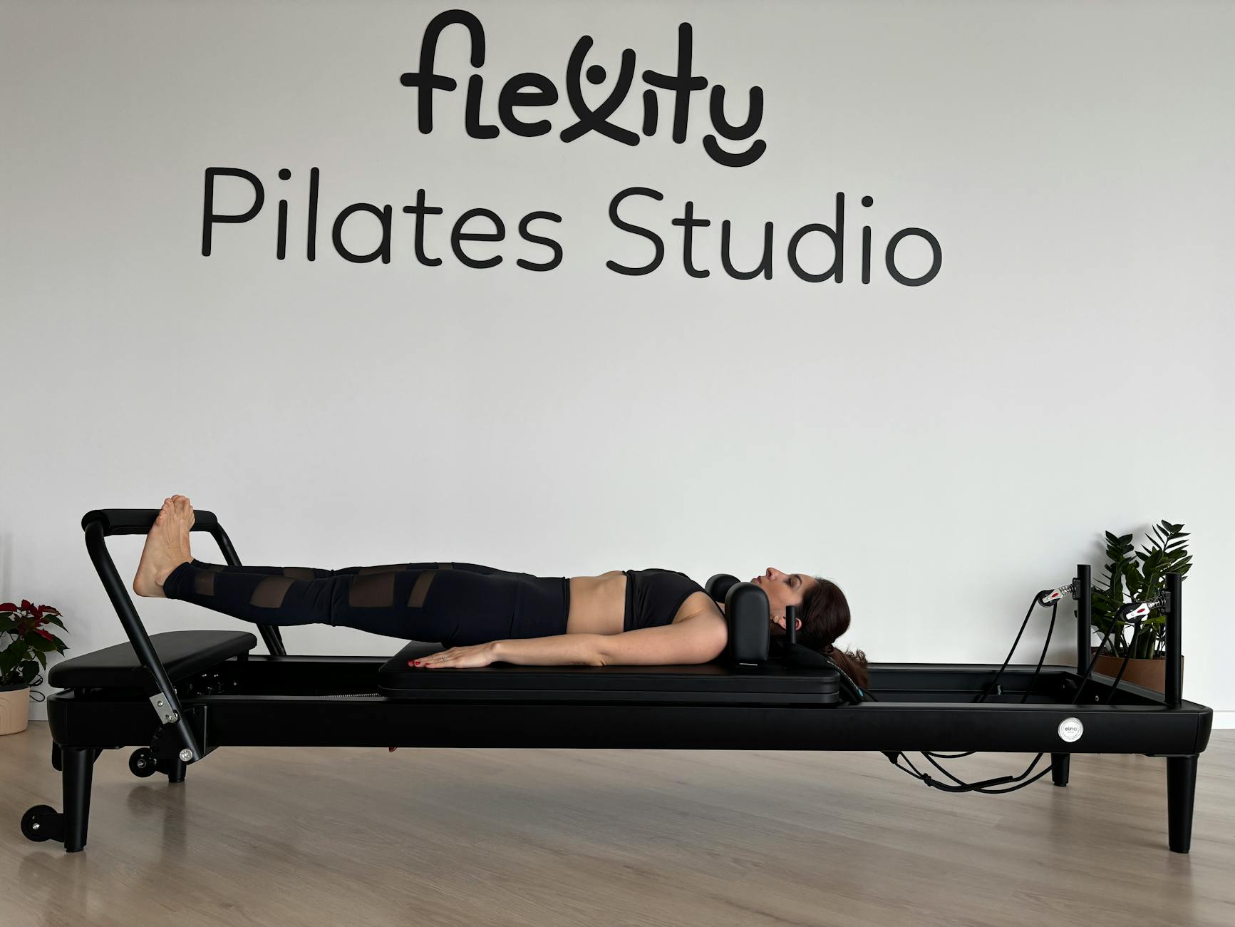 Adult woman exercising on a Pilates reformer at Flexity Pilates Studio indoors. - best pilates exercises