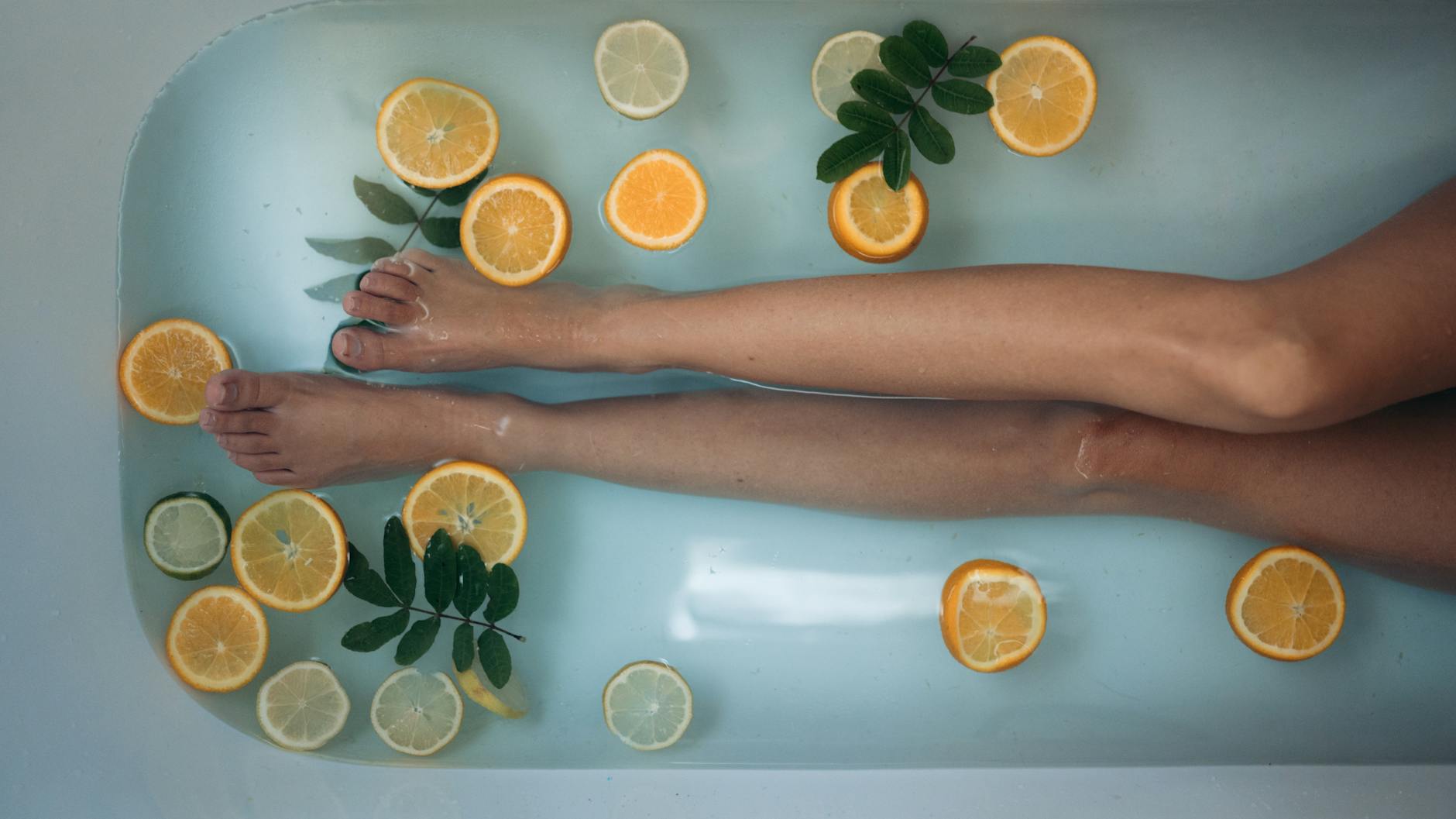 A soothing spa experience with citrus slices and legs submerged in a bathtub, epitomizing relaxation and self-care. - body detox cleanse