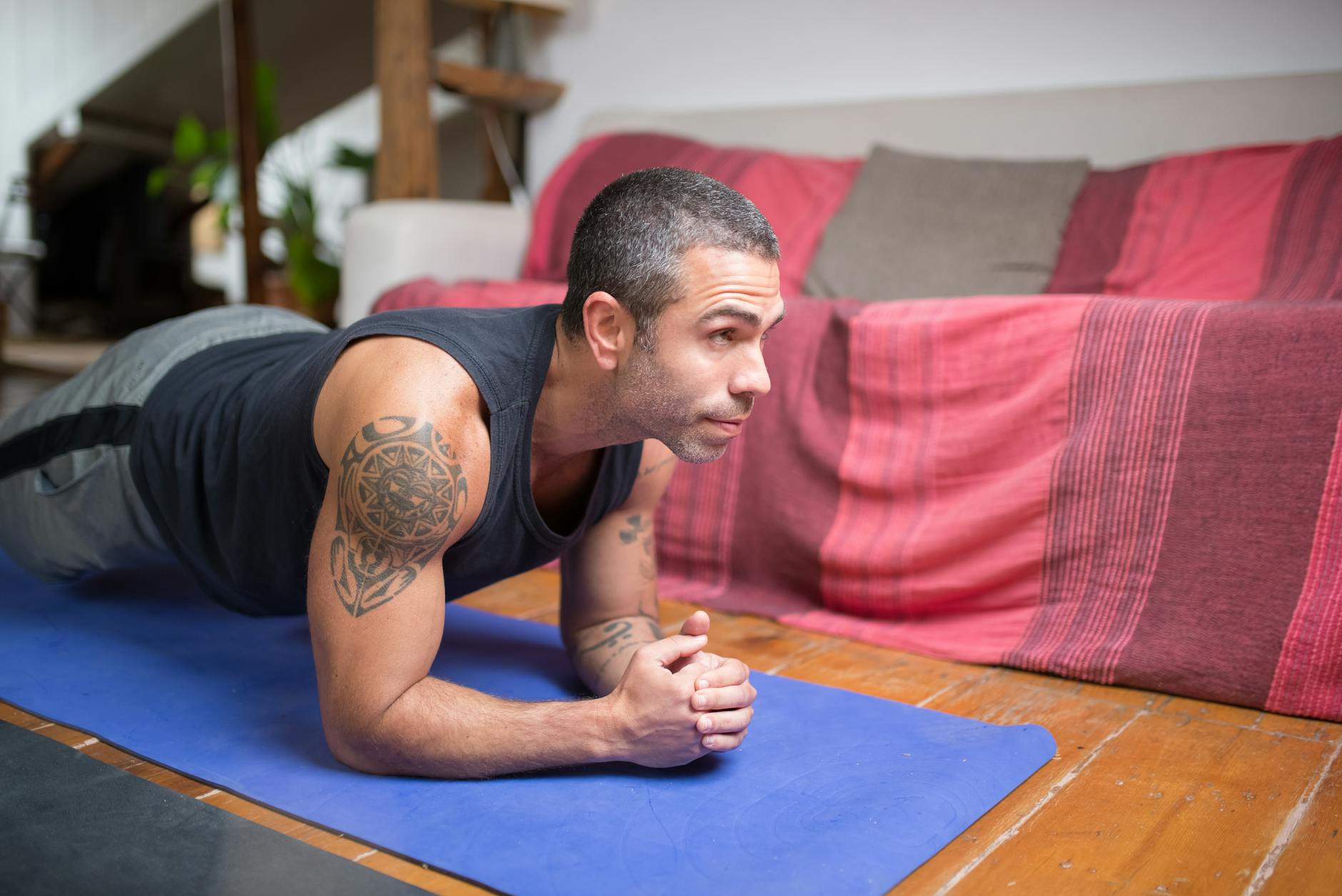 Man doing plank exercise indoors on a yoga mat, embracing a healthy lifestyle. - bodyweight arm exercises