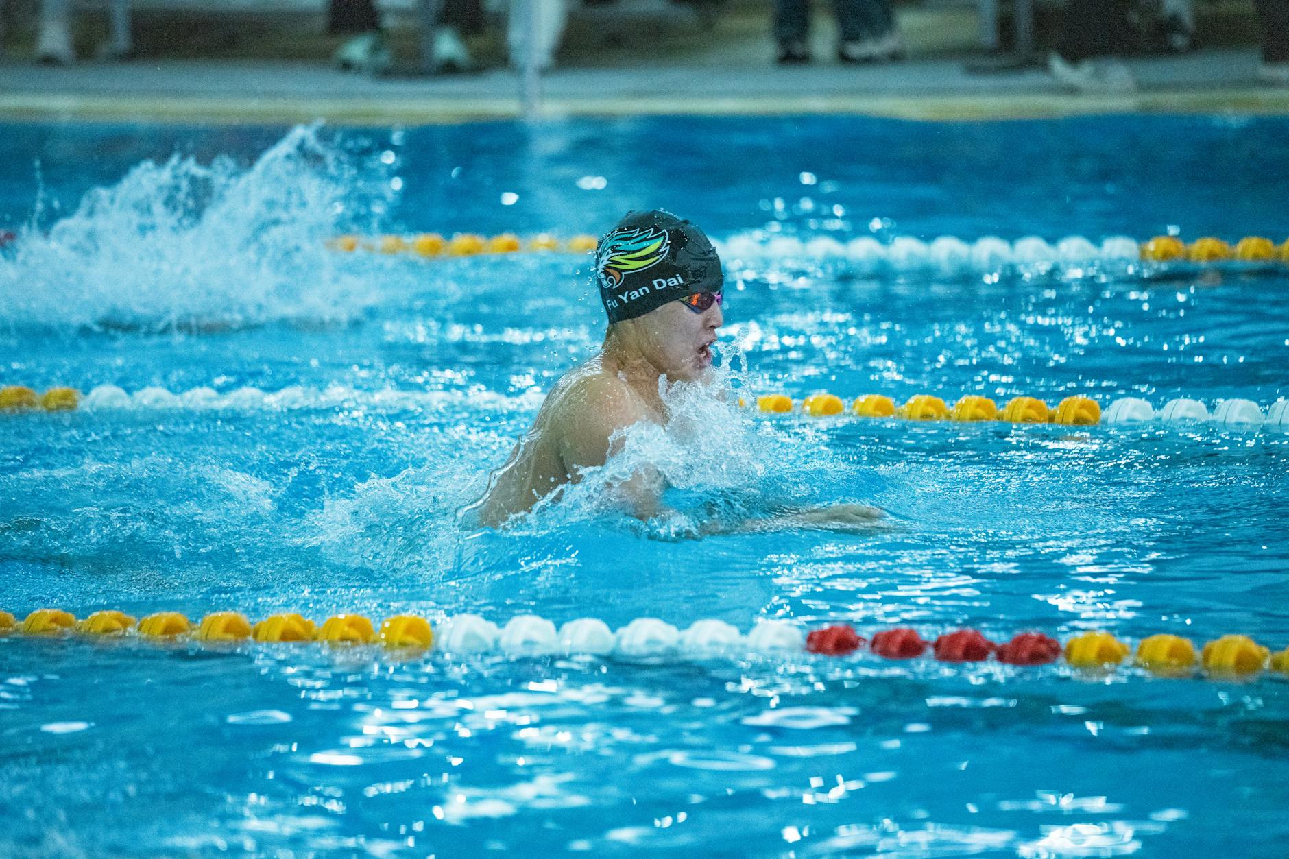 Swimmer mid-race in an indoor pool, focusing on speed and technique. - breaststroke swimming benefits