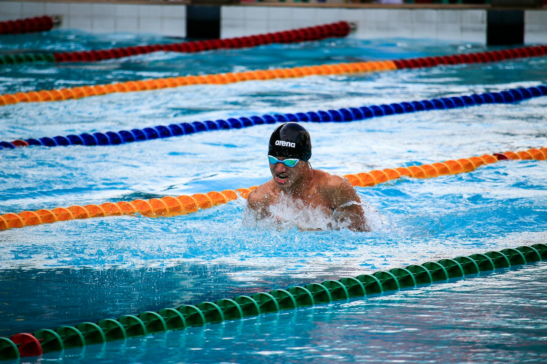 Male athlete swimming in a pool during a race, showcasing water sports action. - breaststroke swimming benefits