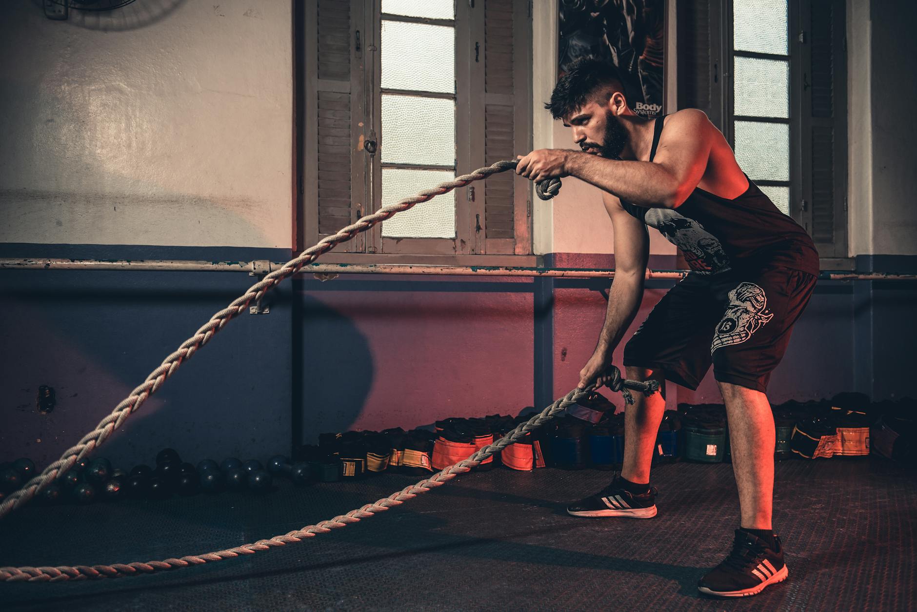 Man performing a challenging Crossfit rope exercise in an indoor gym setting. - crossfit workout plan